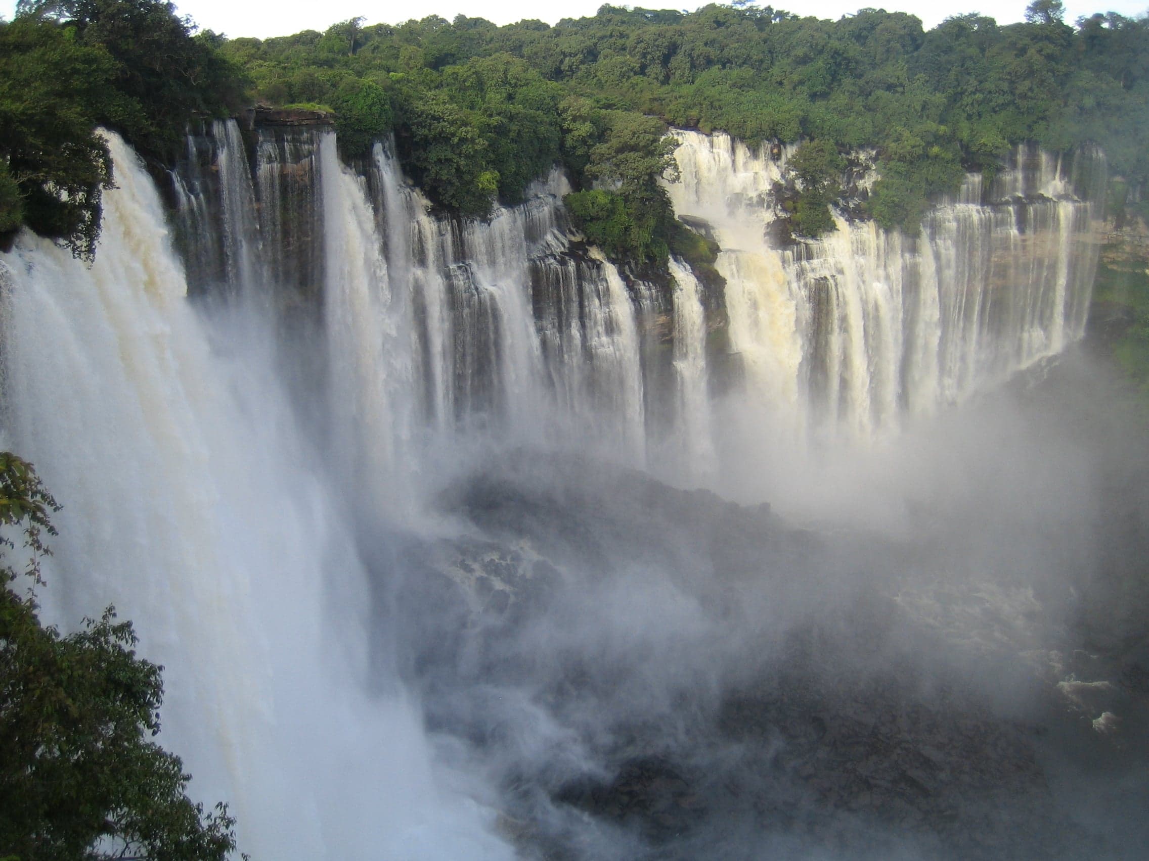 Wide white curtain of water at Kalandula Falls surrounded by green jungle