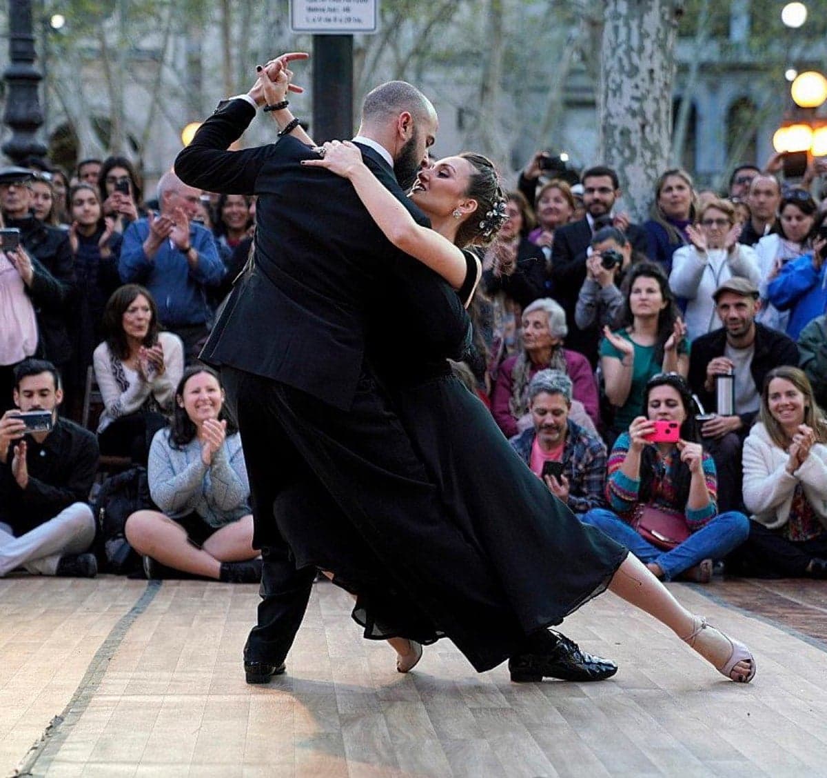 A couple dancing tango on a stage with a watching crowd