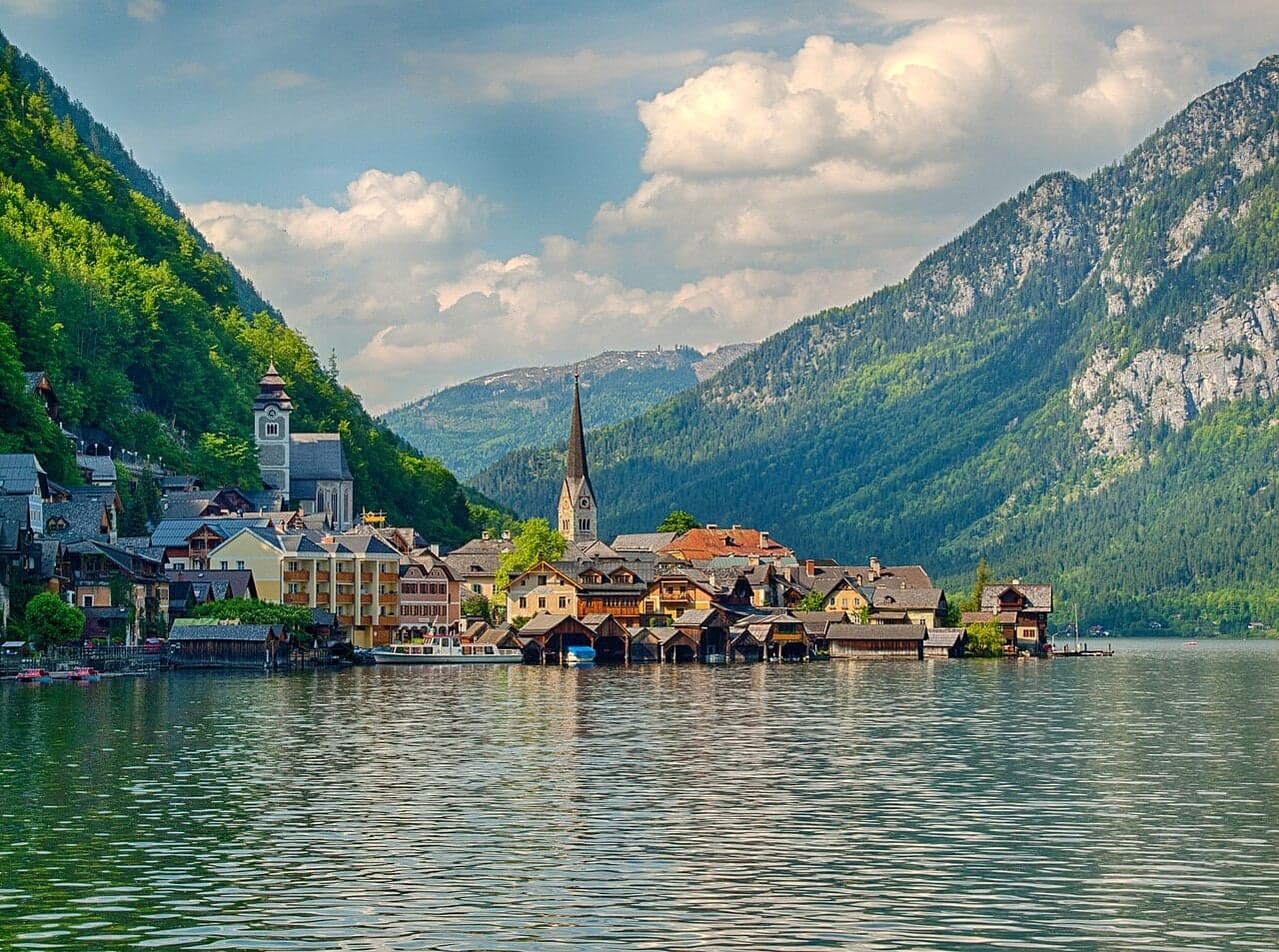 Colourful houses of Hallstatt reflected in the still blue water of the lake, with mountains behind