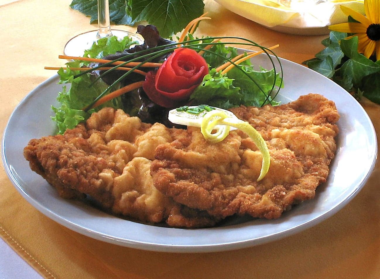 A golden Wiener Schnitzel on a plate with a slice of lemon and potato salad