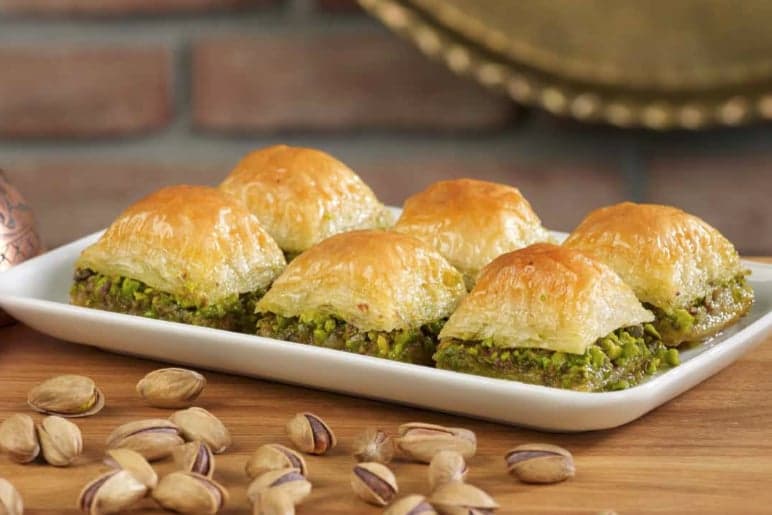 A tray of golden diamond-shaped Azerbaijani pakhlava sweets with nuts on top