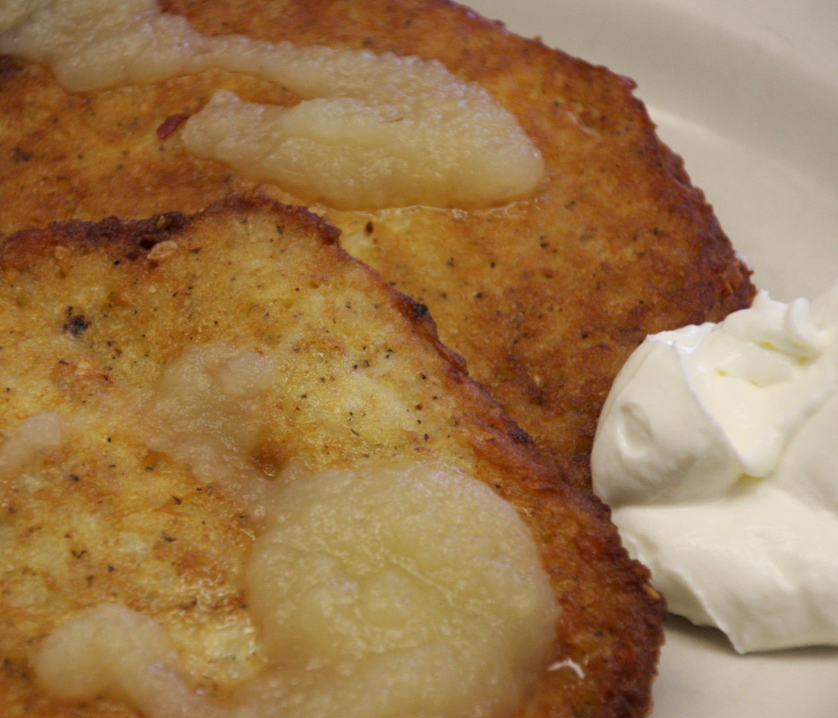 A plate of golden crispy draniki potato pancakes served with sour cream