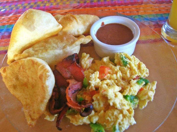 A plate of golden-brown puffed fry jacks with honey and refried beans on the side