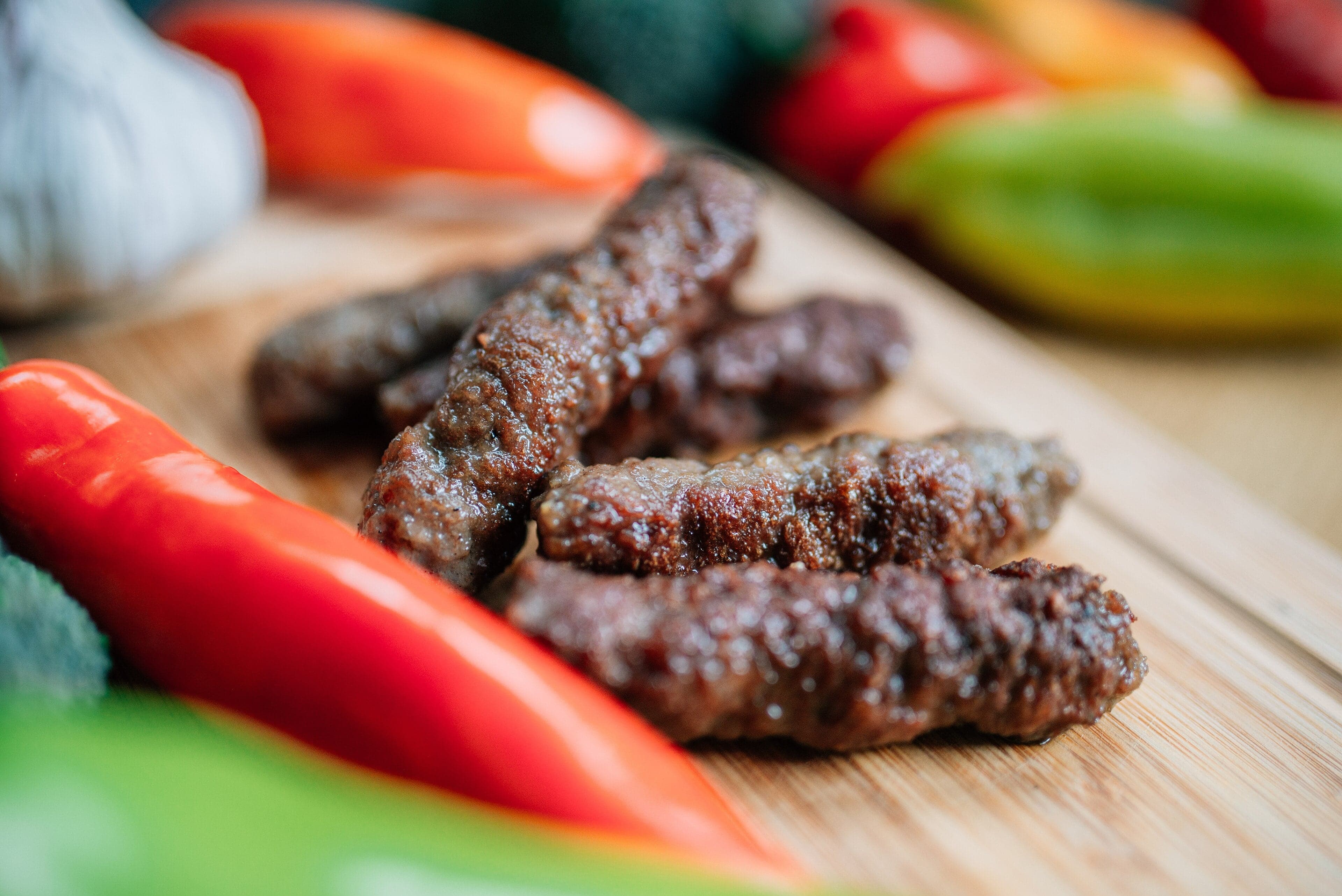 A plate of small Bosnian ćevapi sausages served in somun flatbread with onion and cream