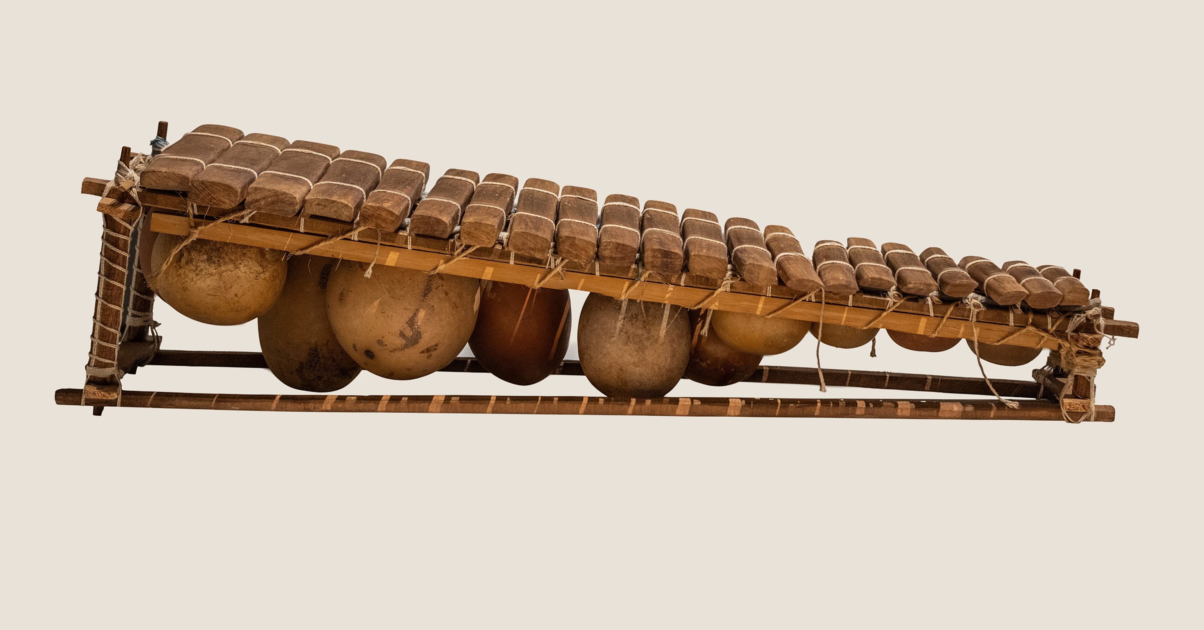 A musician playing a balafon, a large wooden-keyed instrument with gourd resonators hanging beneath