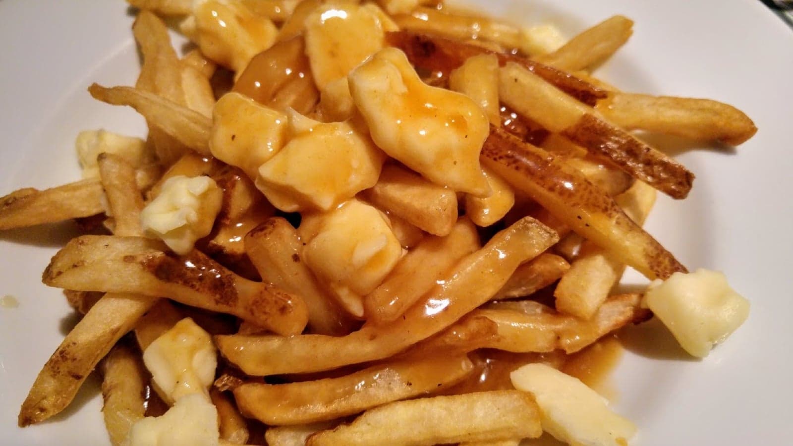 A plate of poutine - chips topped with cheese curds and brown gravy