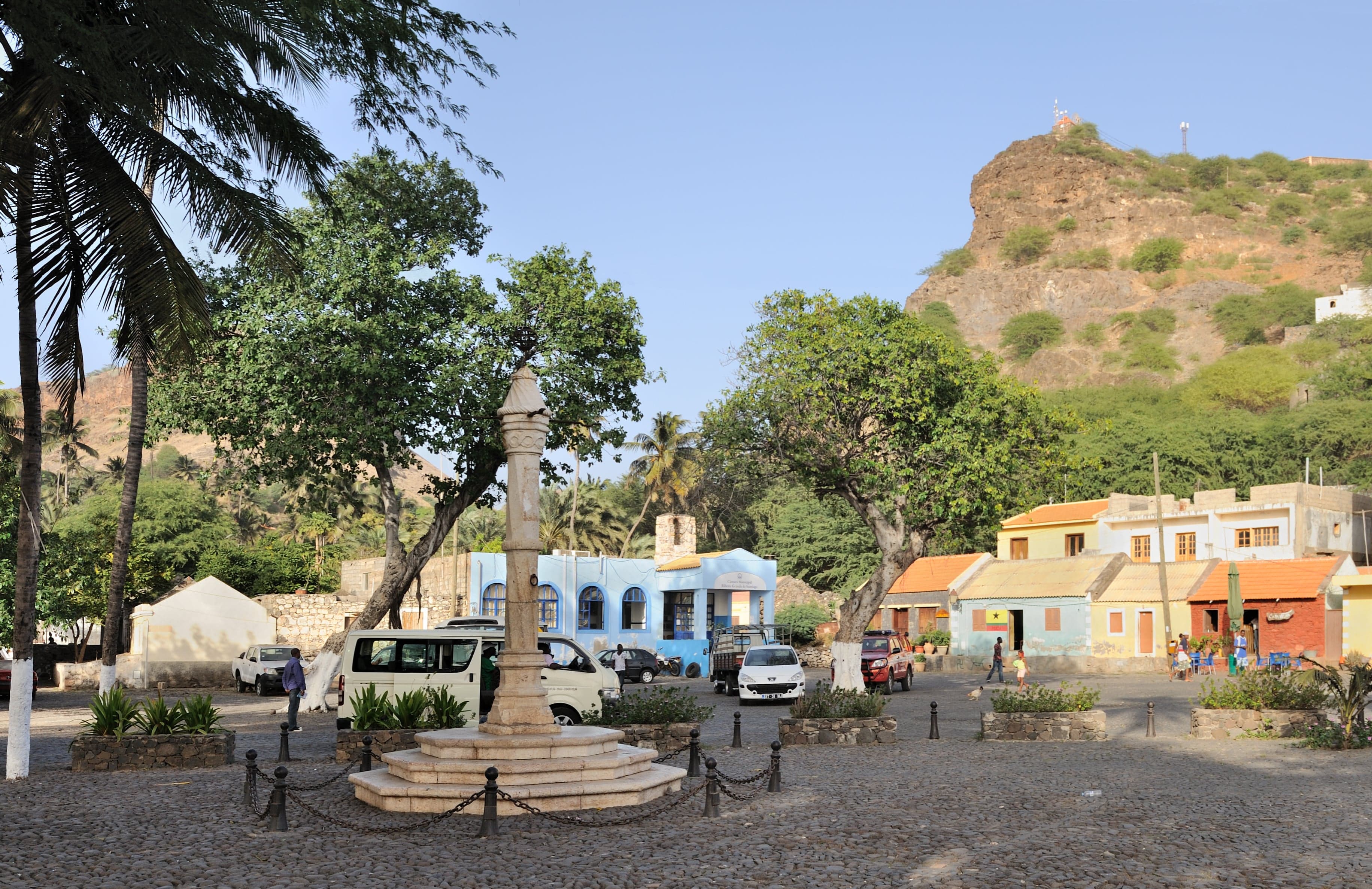 Colourful old stone buildings and a cobbled street in Cidade Velha with the sea behind