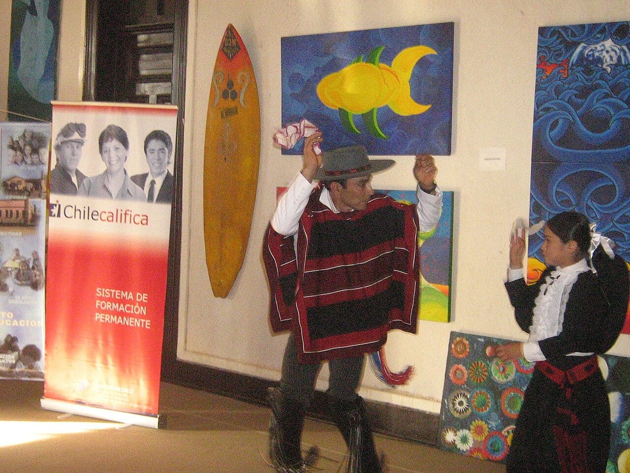 A man and woman in traditional Chilean dress dancing the cueca, each waving a white handkerchief