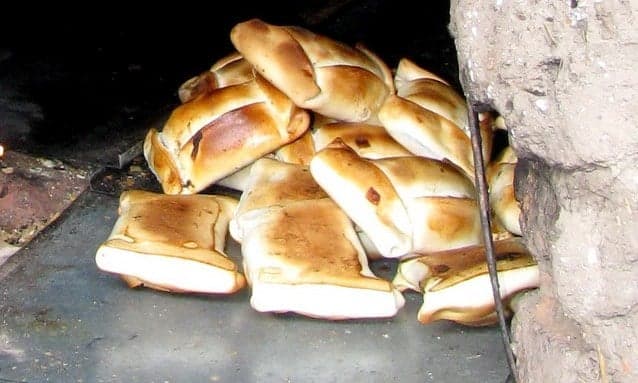 Golden-brown empanadas baked to a crisp, piled on a wooden board
