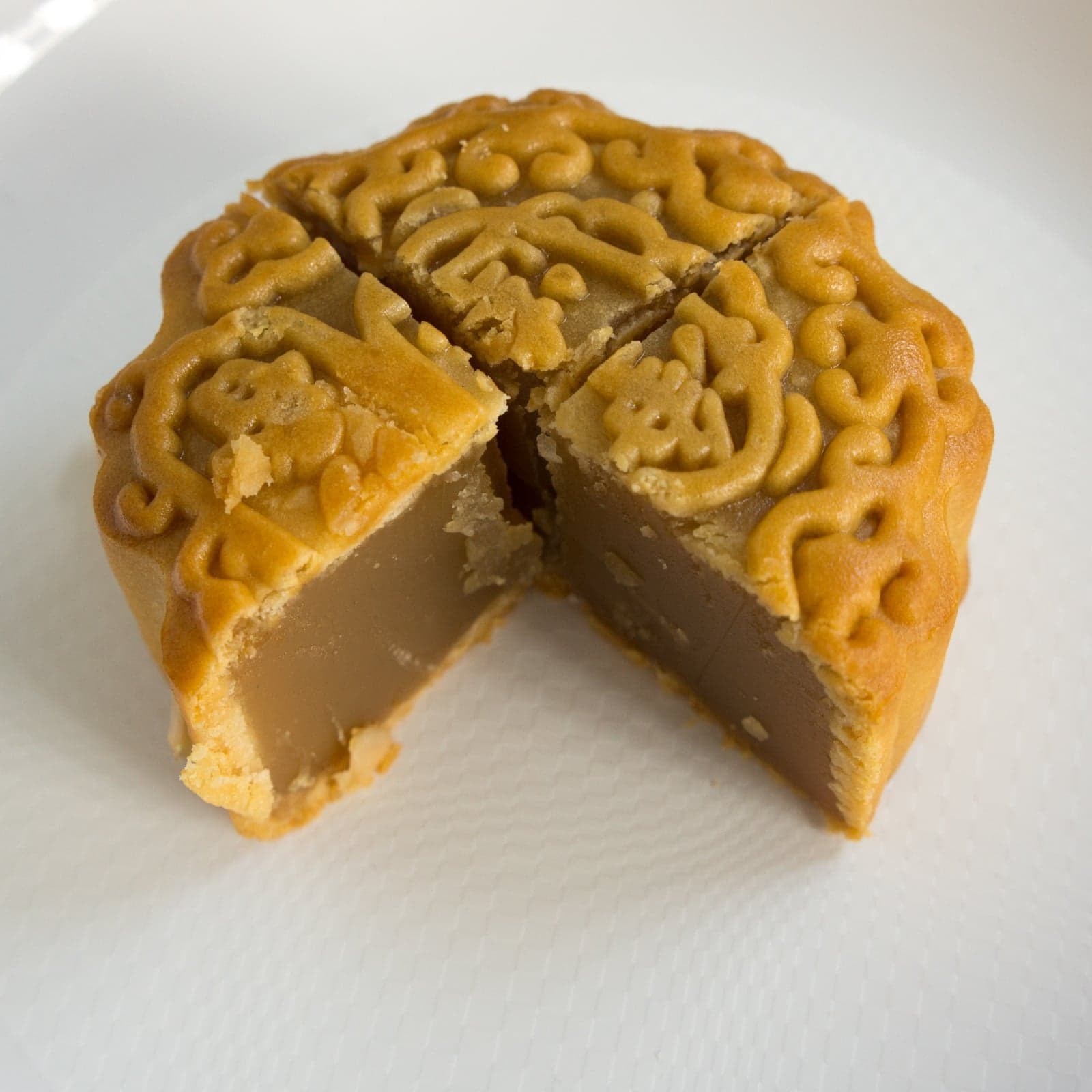 A traditional Chinese mooncake with decorative patterns on its golden top