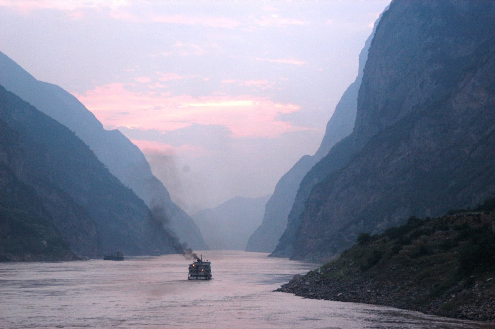 A boat travelling through the Three Gorges of the Yangtze at dusk