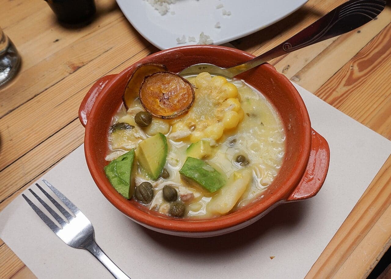 A bowl of ajiaco soup with corn, three kinds of potato and fresh herbs