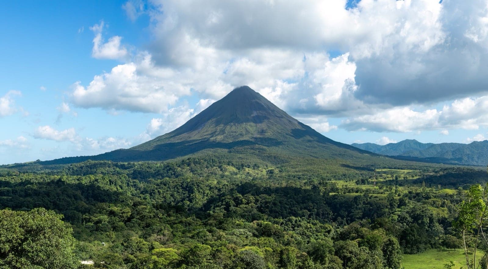 The classic cone shape of Arenal Volcano rising above forest
