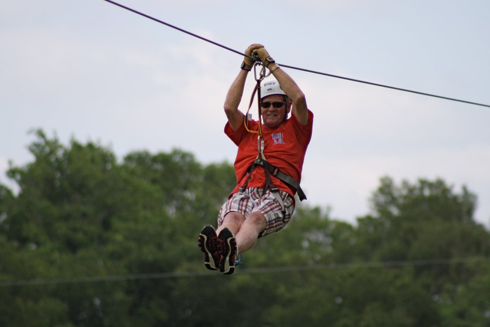 A zip-line cable strung between two tall trees in a rainforest