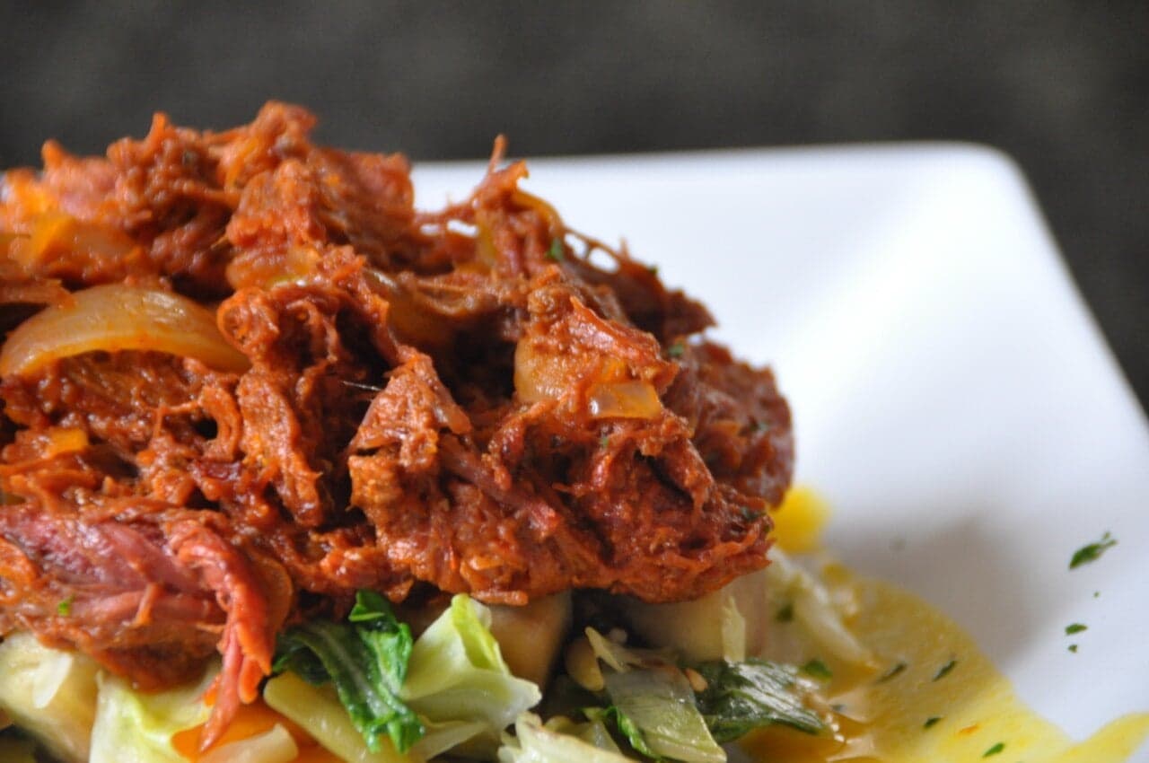 A plate of ropa vieja - shredded beef with colourful peppers and rice on a ceramic dish