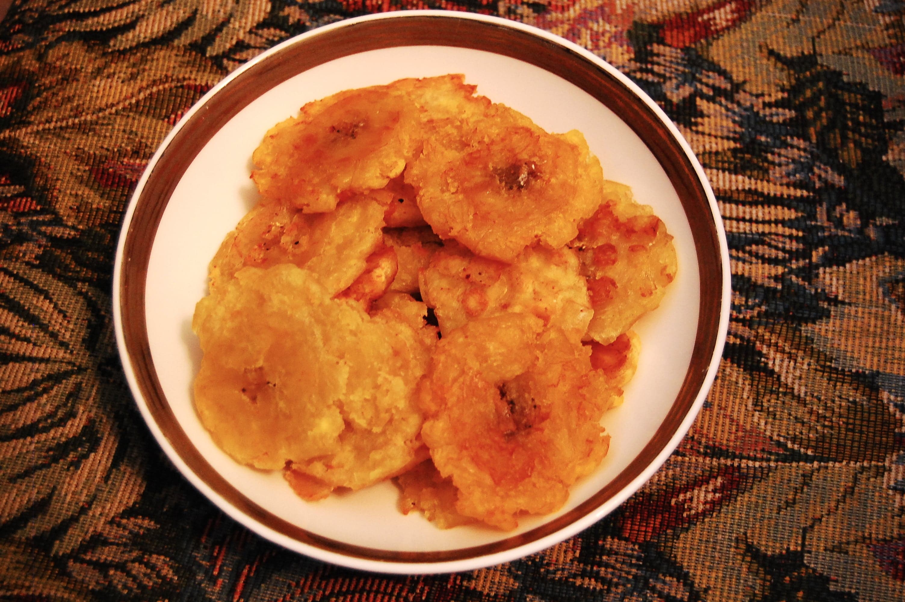 Golden crispy tostones (twice-fried green plantain slices) stacked on a plate