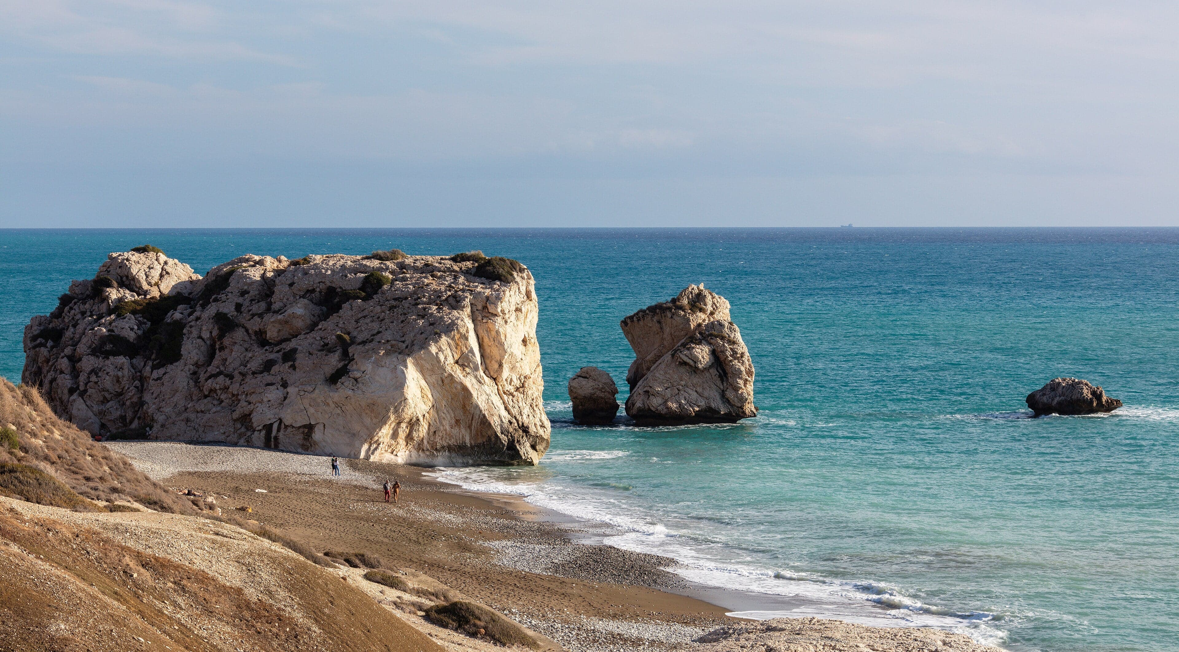 A large rocky outcrop rising from the blue Mediterranean Sea near Paphos