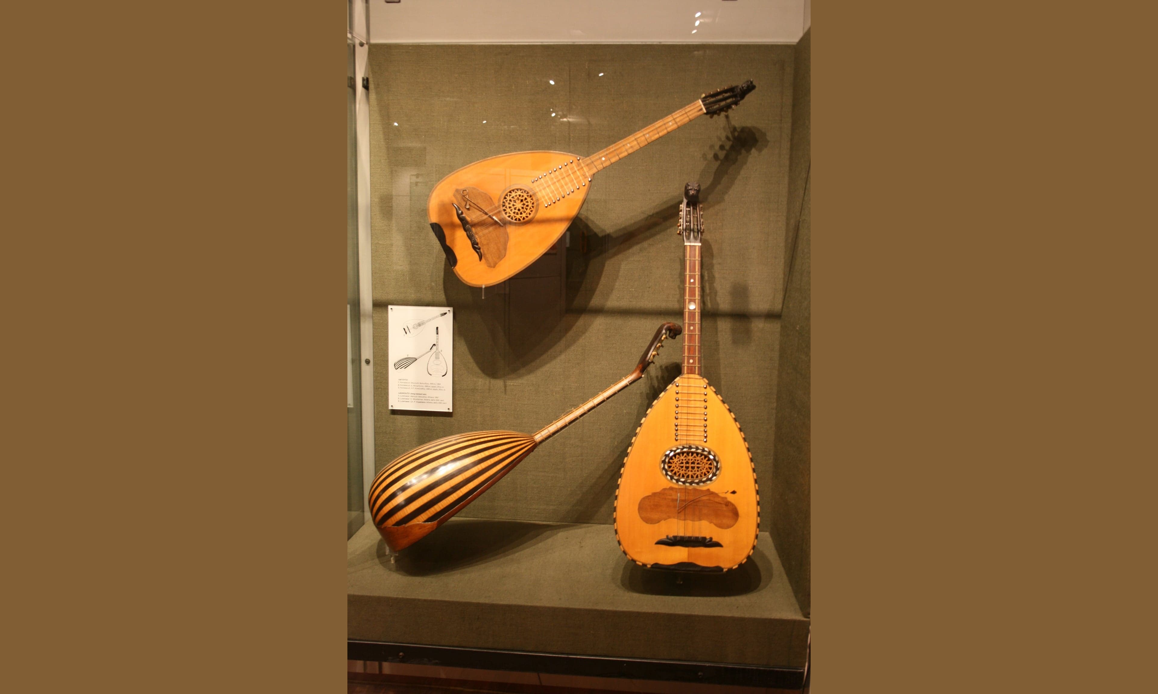 A bouzouki and an oud resting side by side against a white-washed wall