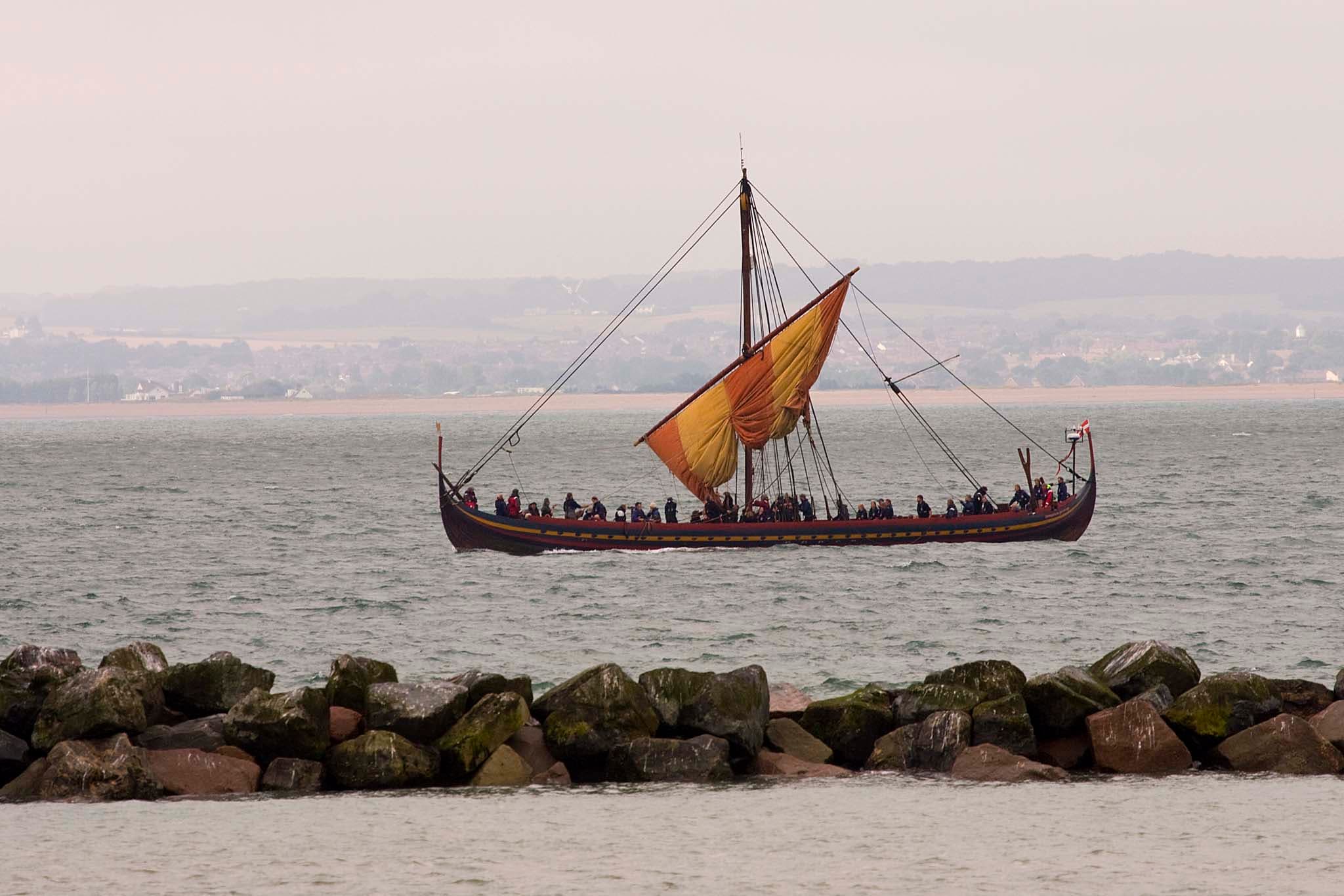A replica Viking longship with a striped sail at sea