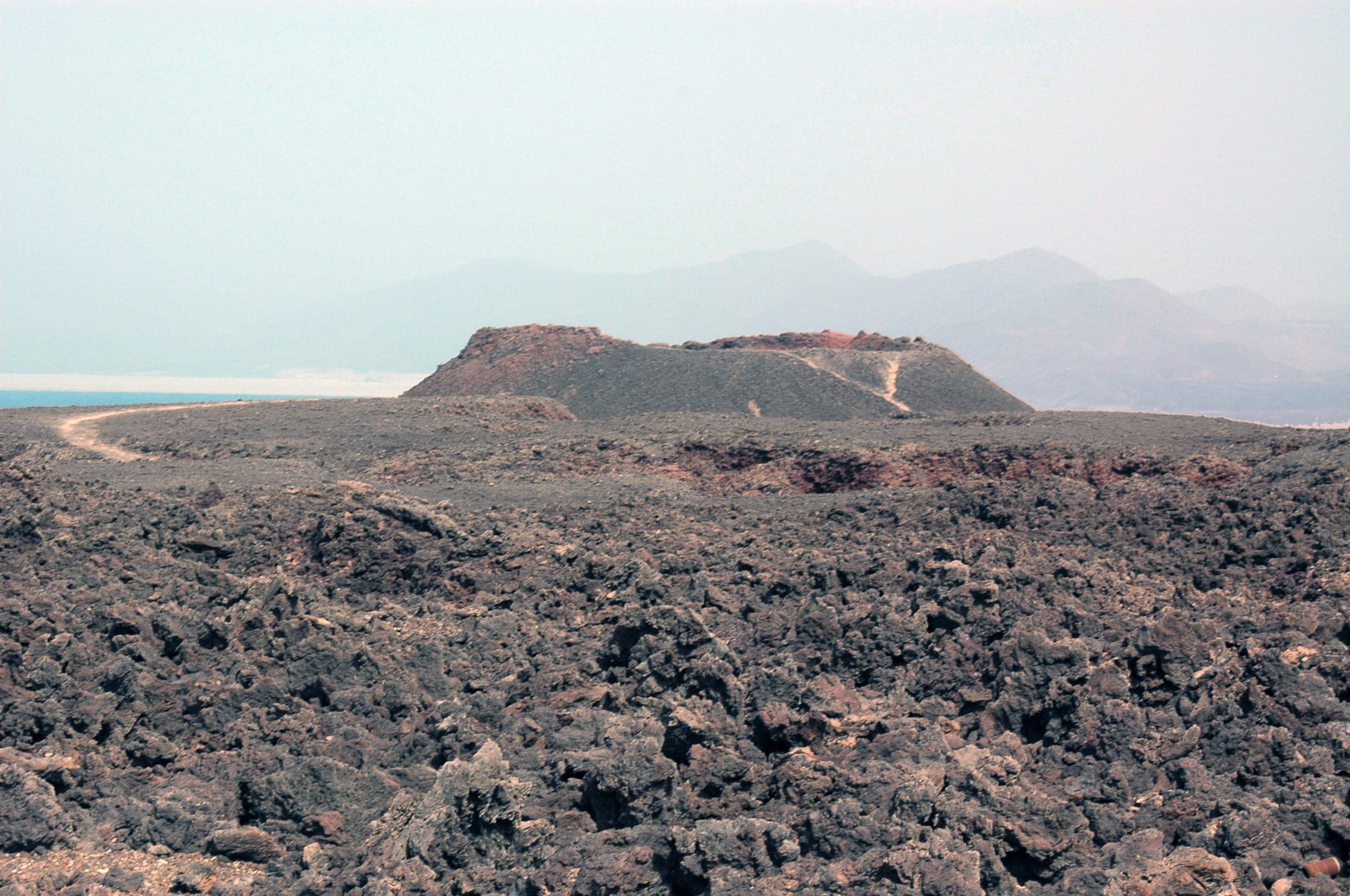 The dark lava fields and cone of Ardoukoba volcano under a wide sky in Djibouti