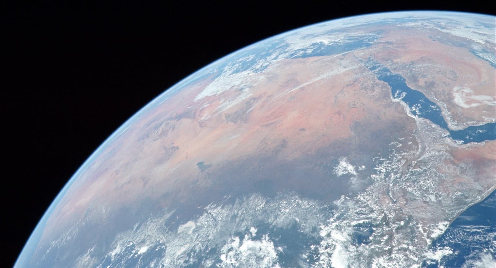 The Sahara seen from space, a vast band of golden sand across northern Africa