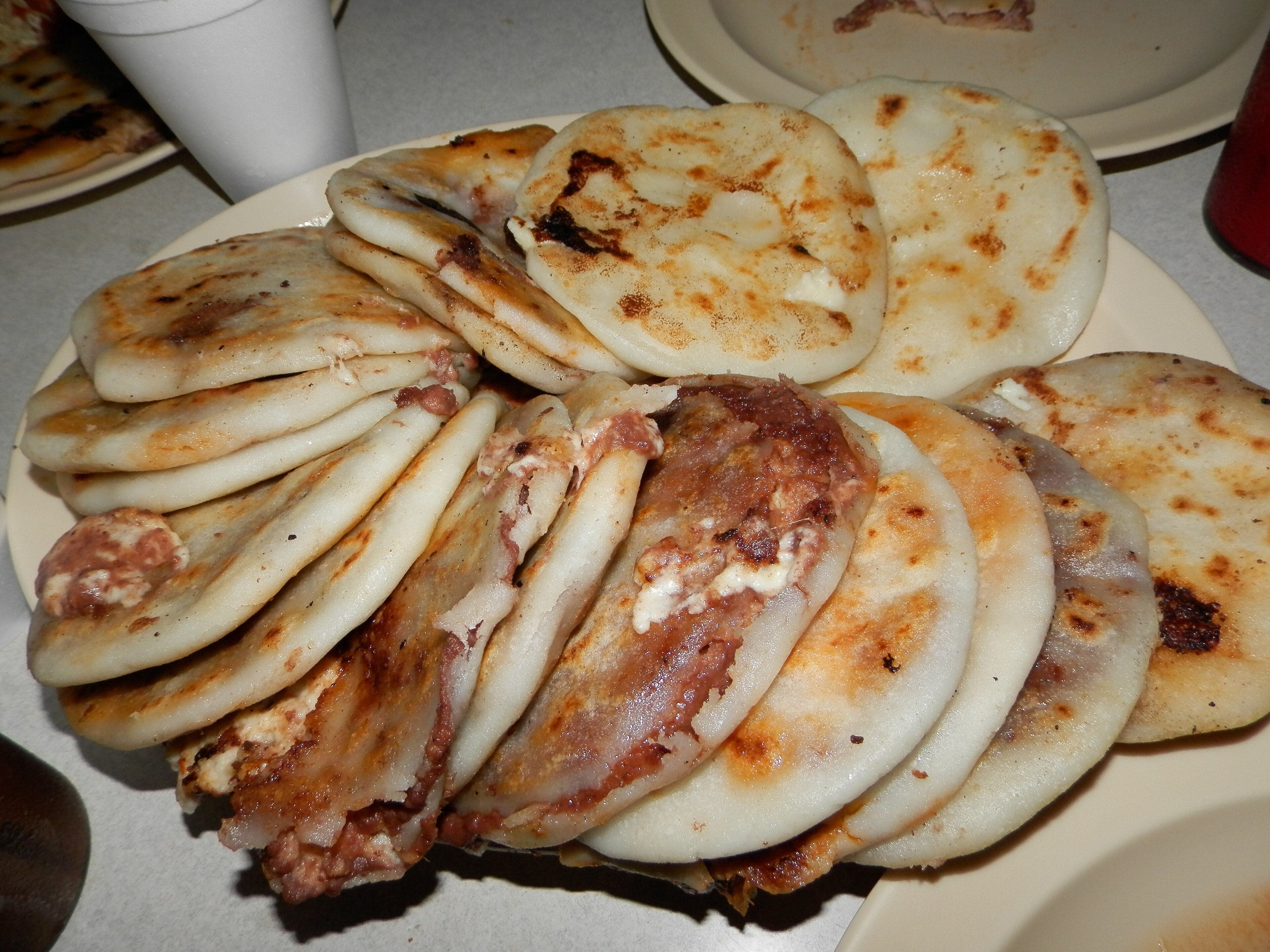 Freshly cooked pupusas on a griddle, golden-brown and steaming