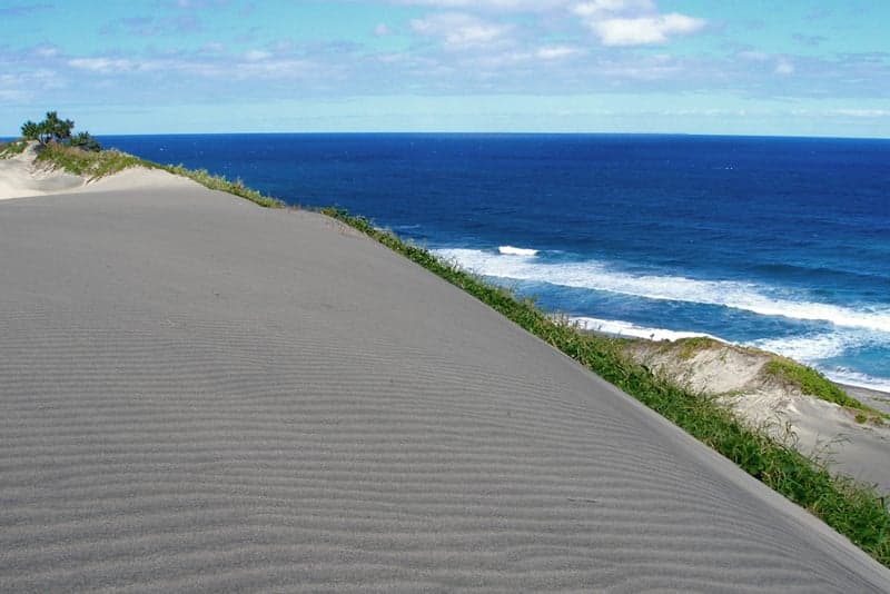 Large golden sand dunes rolling down towards a blue Pacific beach at Sigatoka