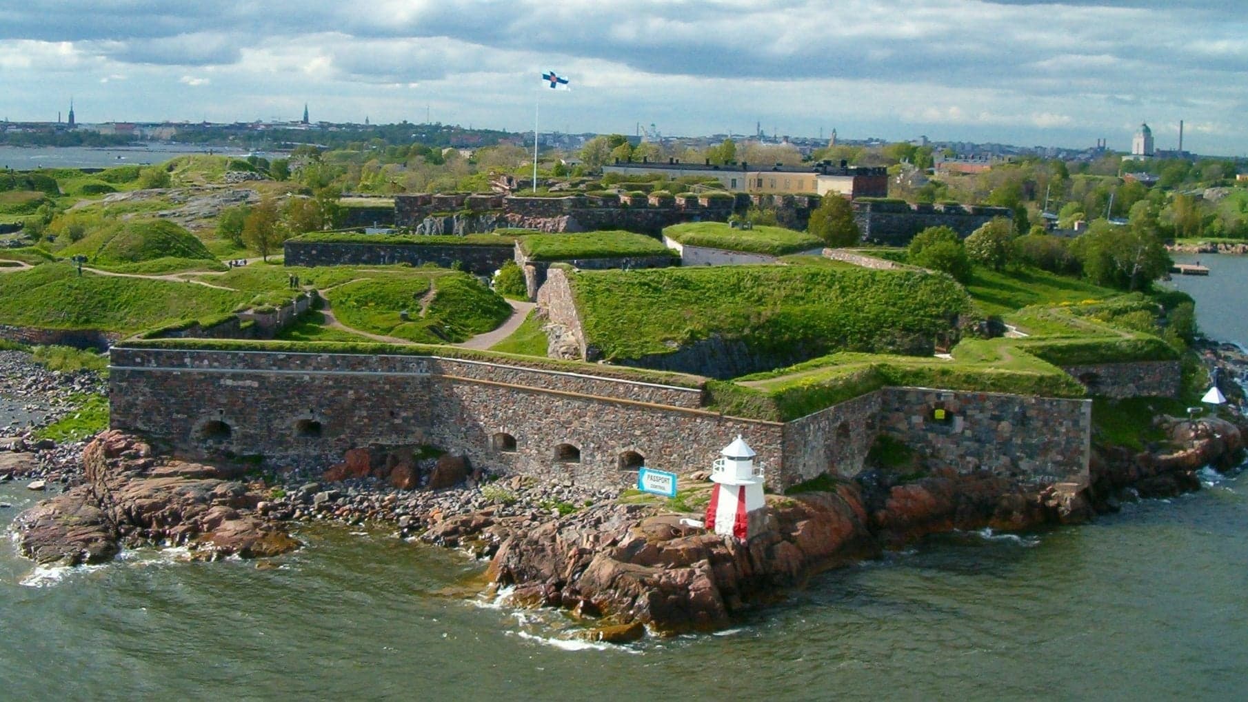 The sea fortress of Suomenlinna off Helsinki, with the blue and white Finnish flag flying above grassy ramparts