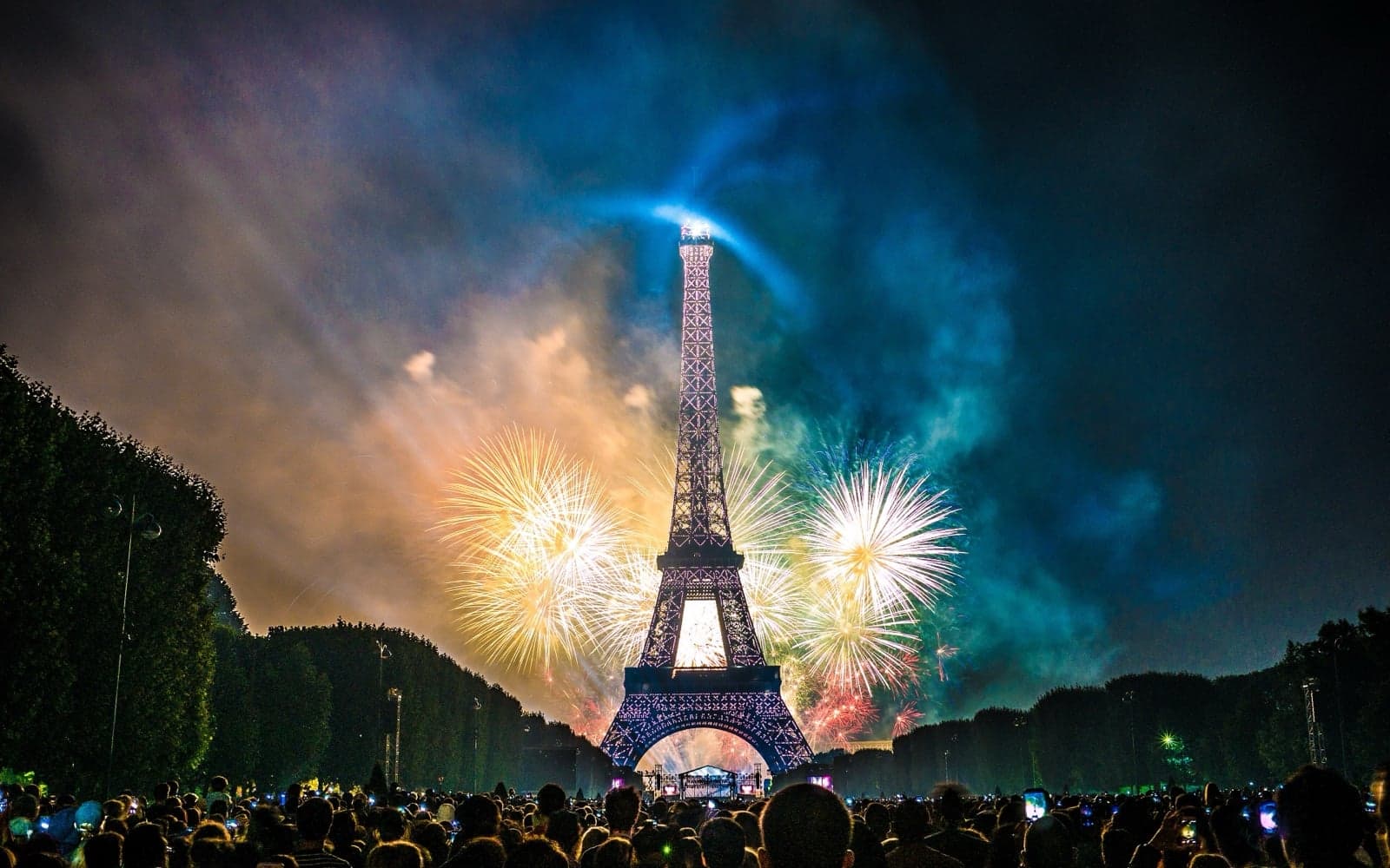 Fireworks lighting up the sky behind the Eiffel Tower on Bastille Day