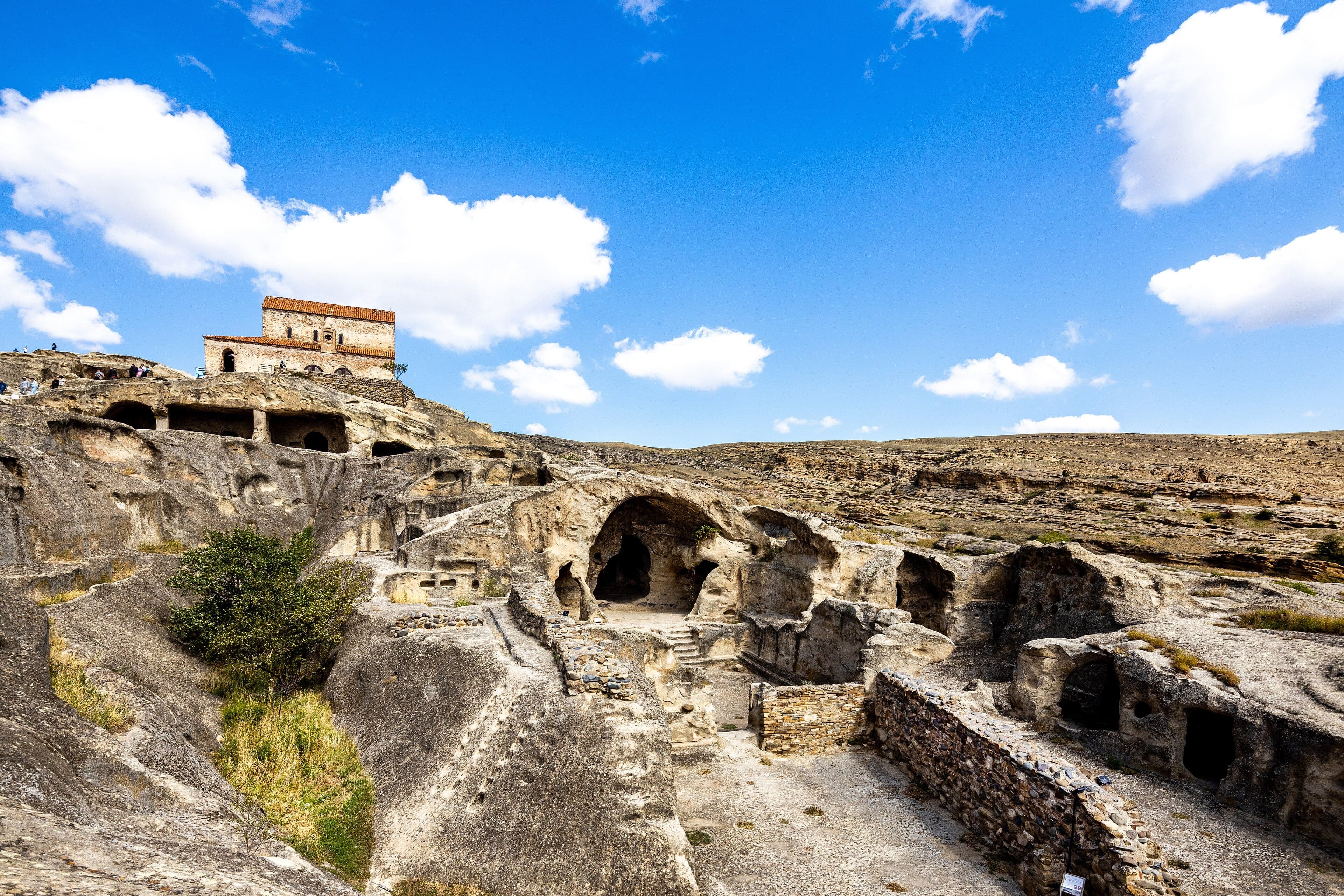 The ancient rock-cut city of Uplistsikhe with carved rooms and tunnels visible in the golden stone