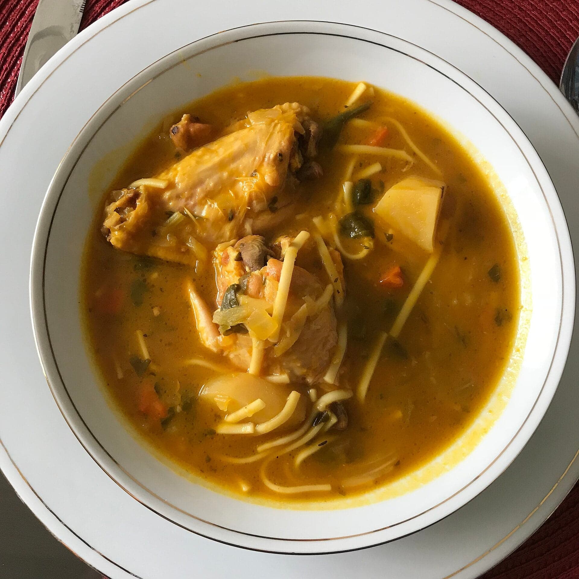 A bowl of golden pumpkin soup joumou with vegetables and meat