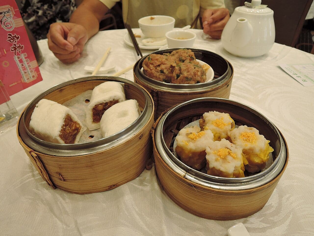 Bamboo baskets of steamed dumplings and char siu bao arranged on a table