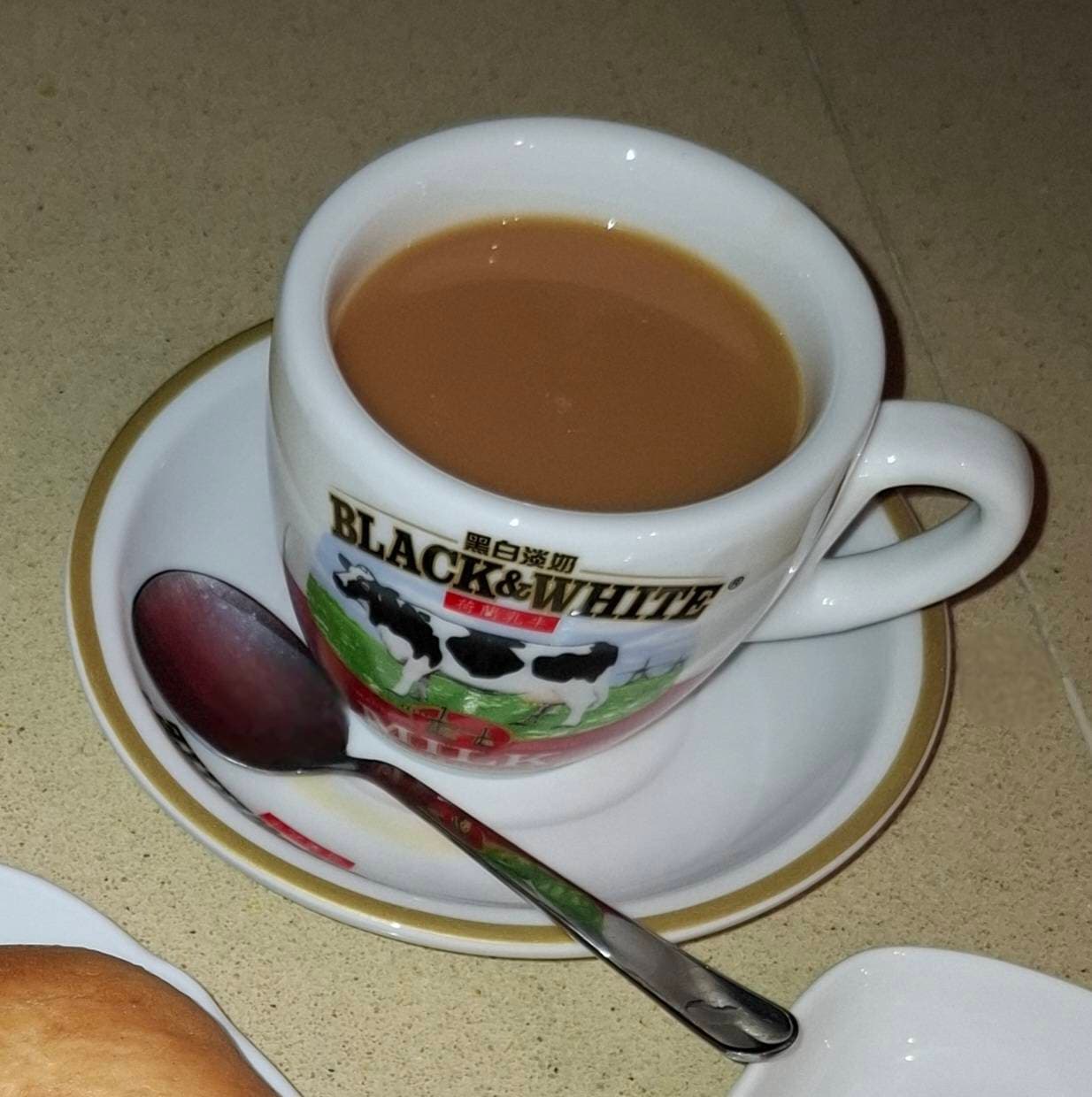 A glass of Hong Kong milk tea with evaporated milk swirling in dark tea