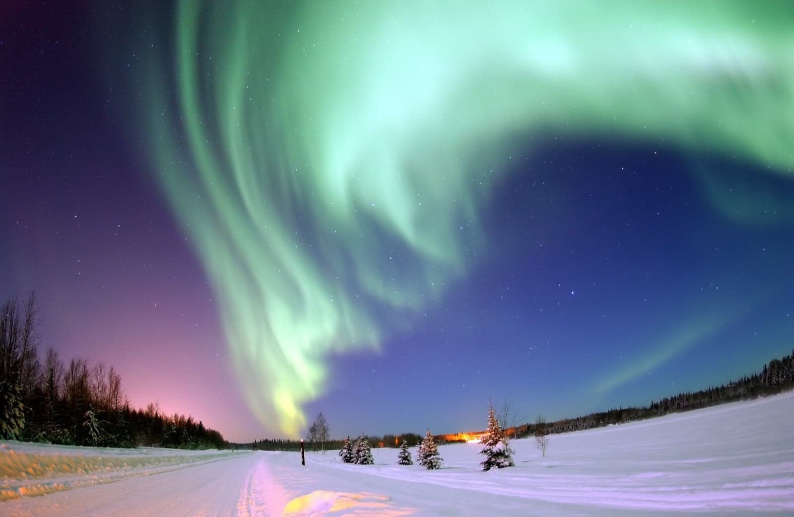 Green Northern Lights swirling across the night sky over an Icelandic landscape