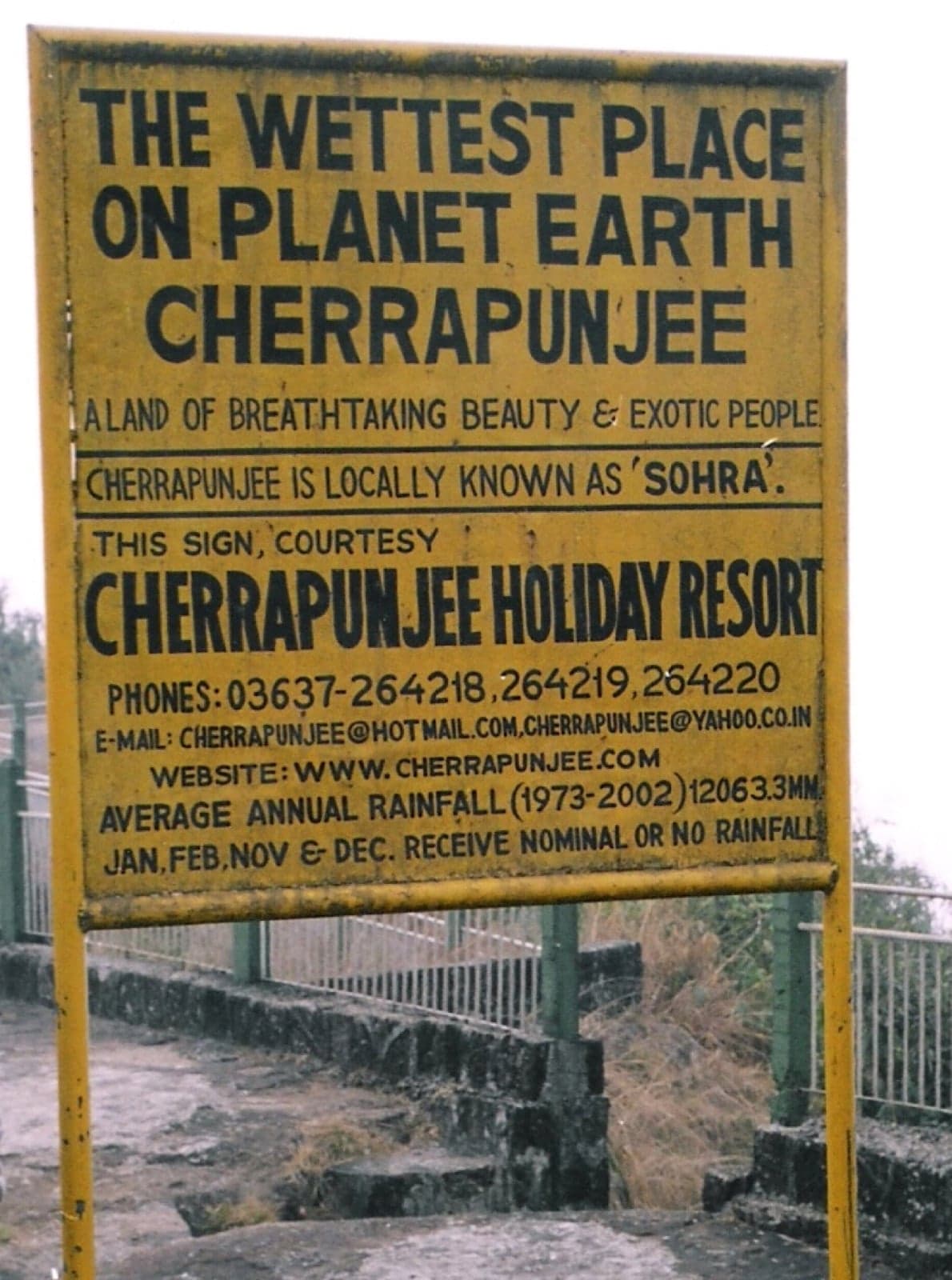 A roadside sign reading 'The wettest place on planet earth, Cherrapunjee'