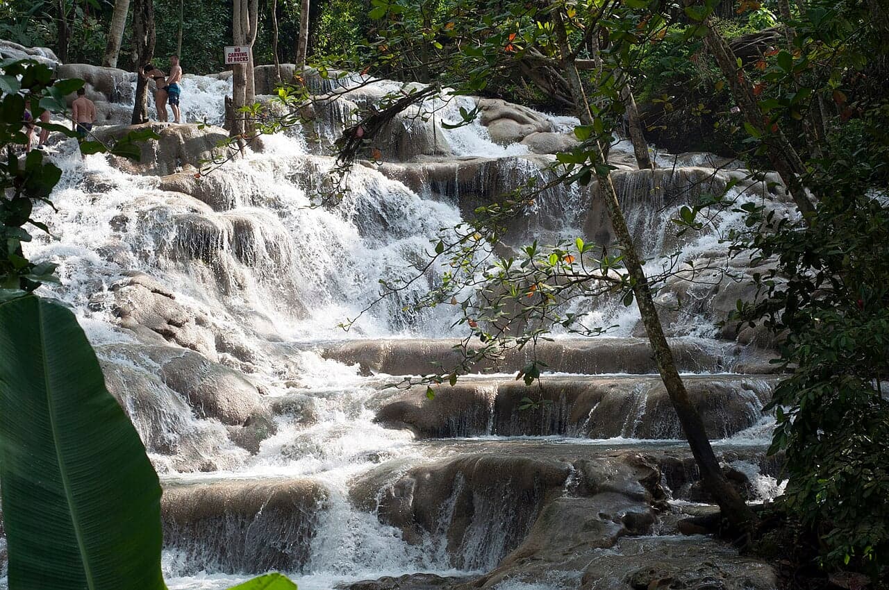Visitors climbing the stepped terraces of Dunn's River Falls in the sunshine