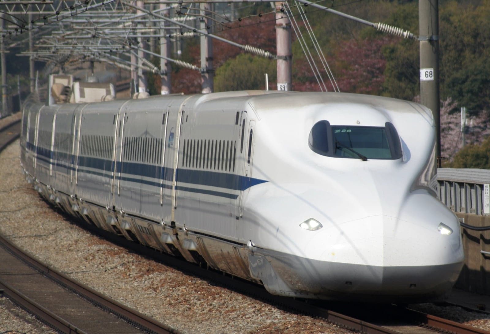 A sleek white N700 series Shinkansen bullet train curving along a track