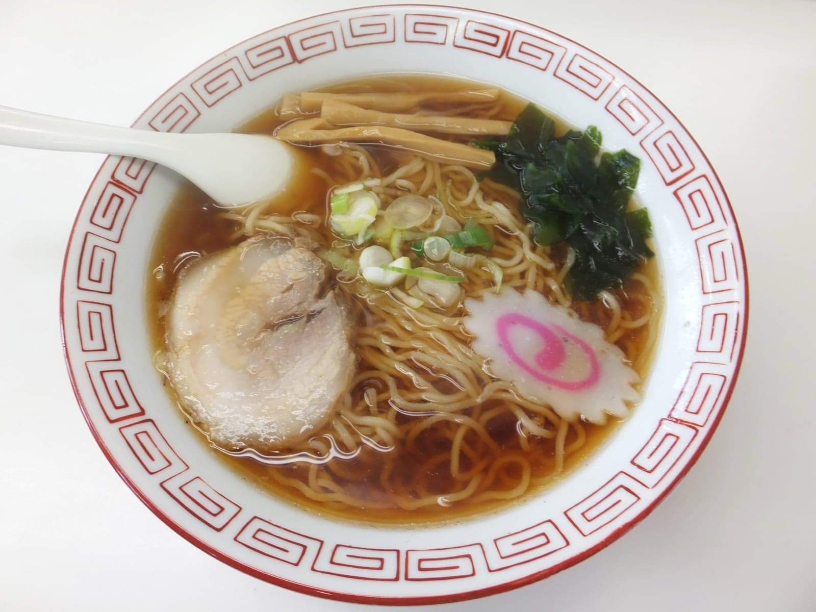 A bowl of shoyu ramen - yellow noodles in soy-coloured broth with seaweed, spring onion and toppings