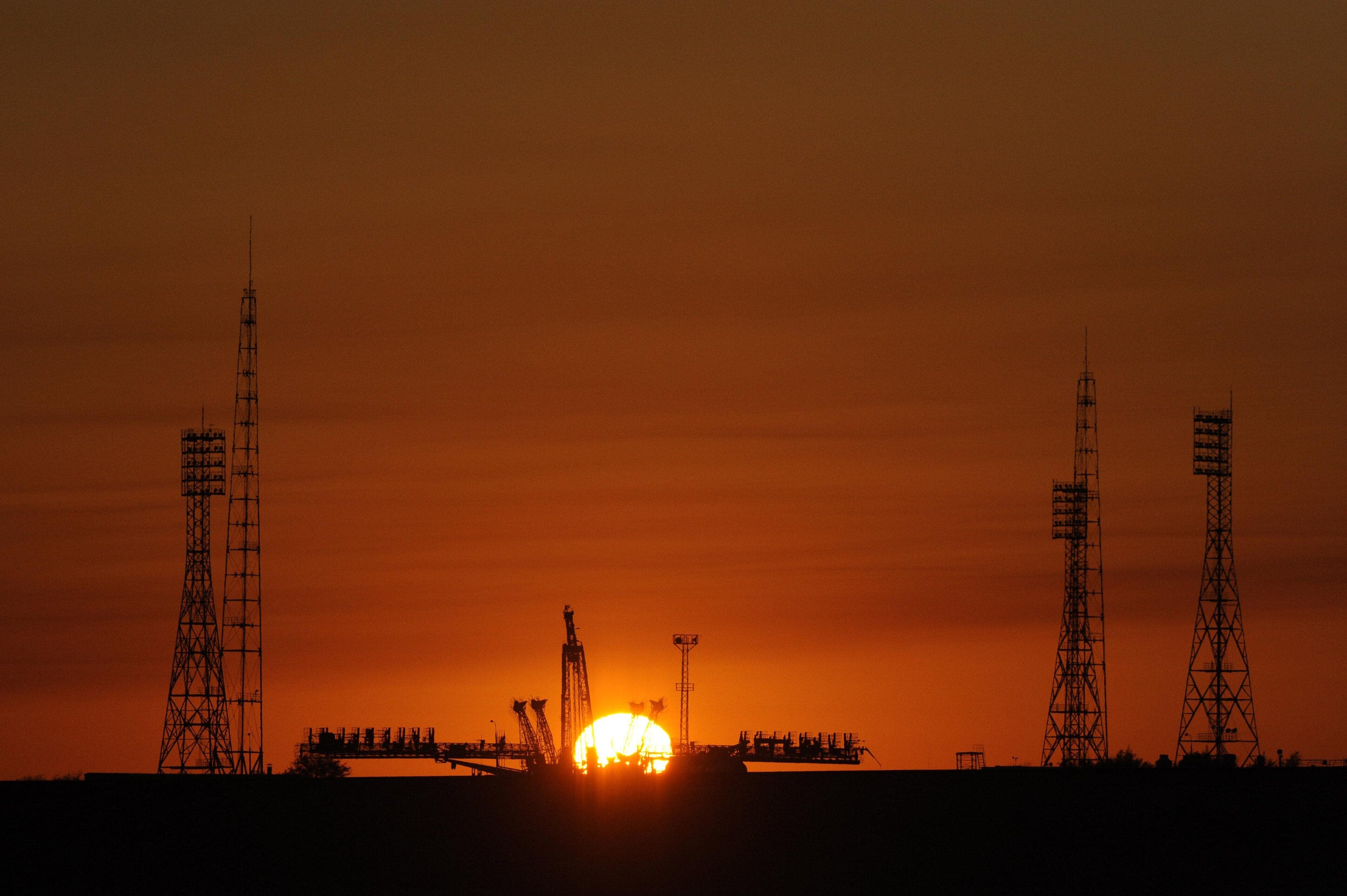 A rocket launching from the Baikonur Cosmodrome with a trail of white smoke across a blue sky