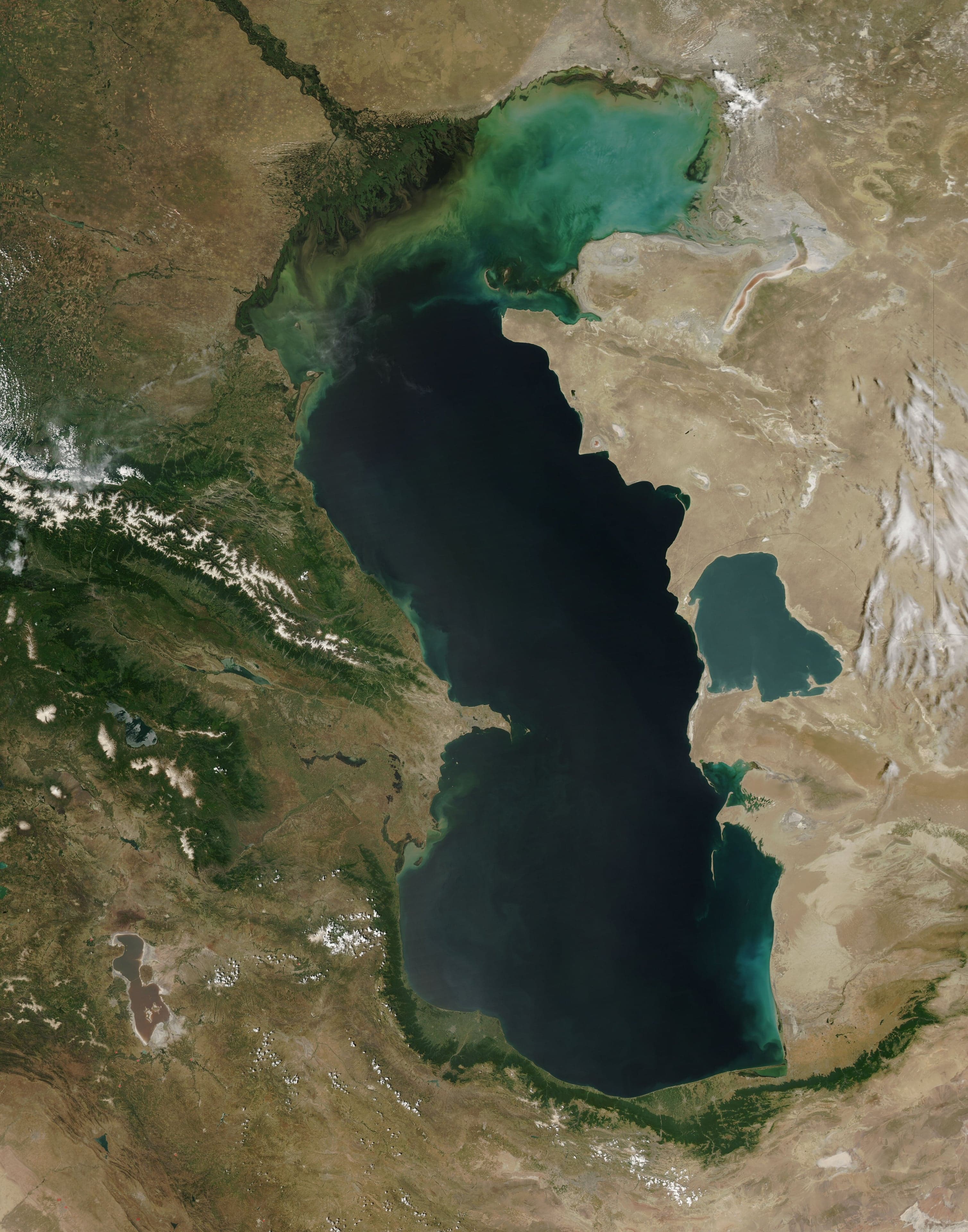 The calm, blue-grey waters of the Caspian Sea meeting a sandy shore