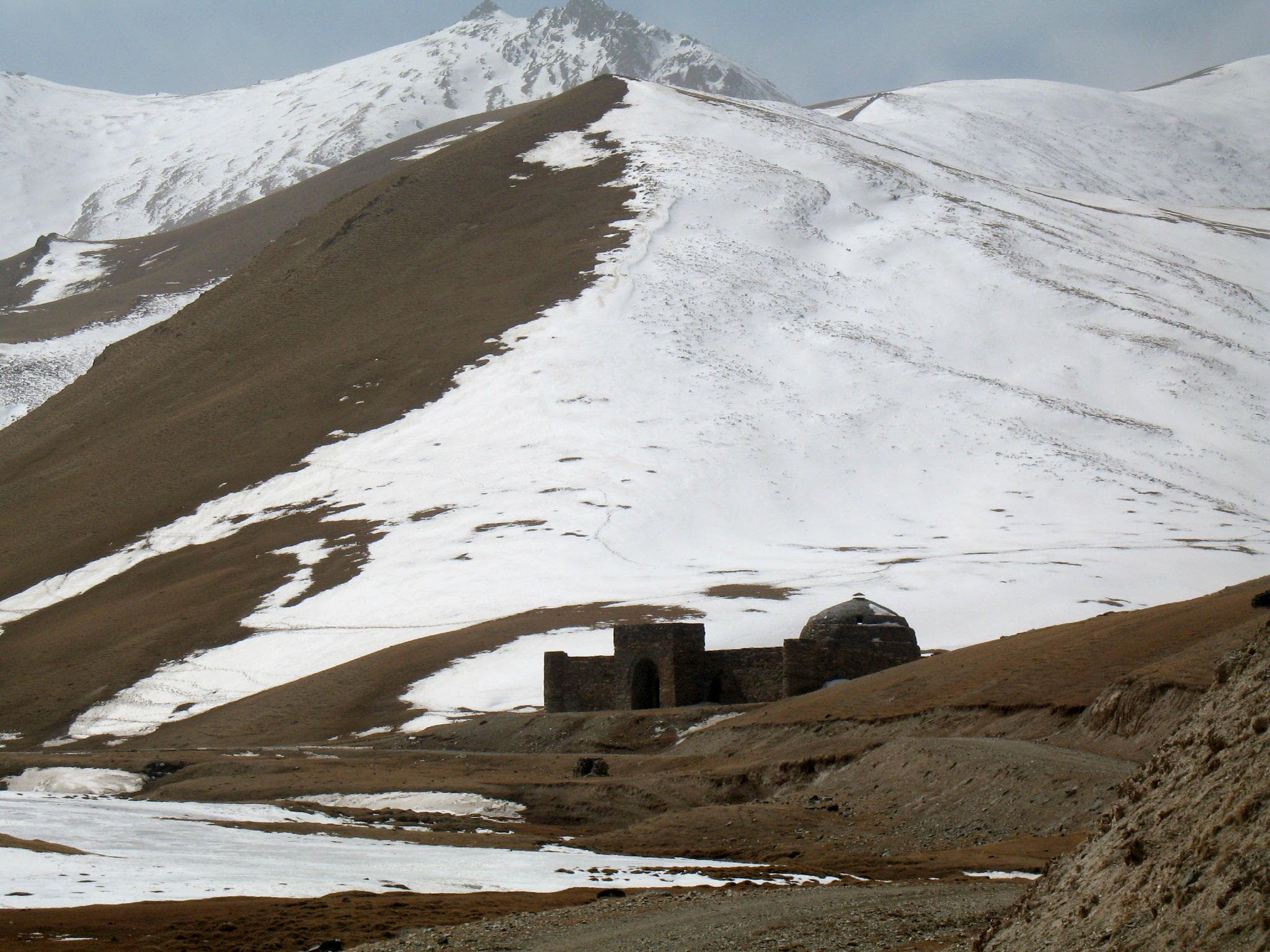 The stone dome and arched entrance of Tash Rabat caravanserai in a mountain valley