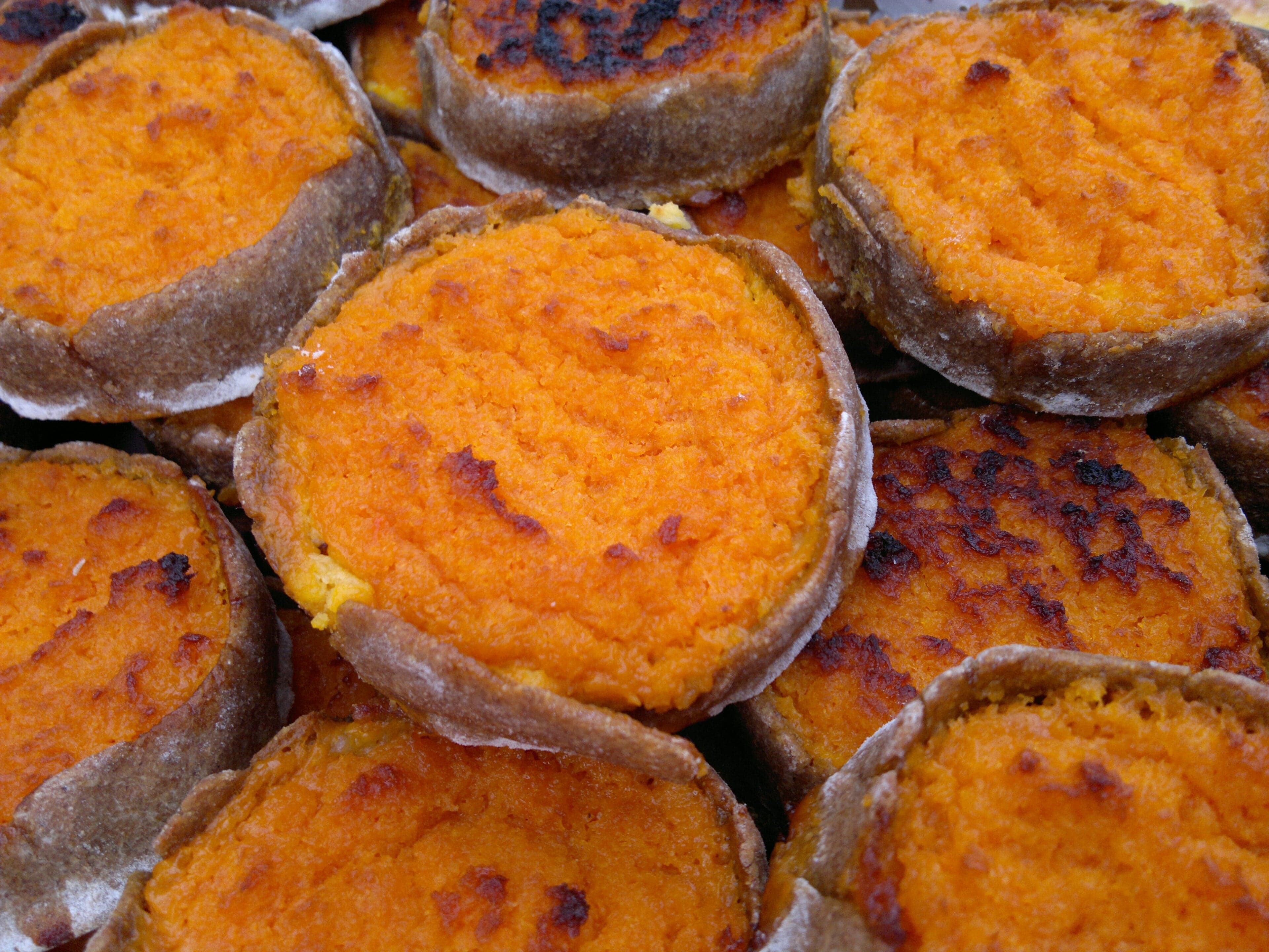 Small round Latvian sklandrausis tarts with an orange carrot and potato filling