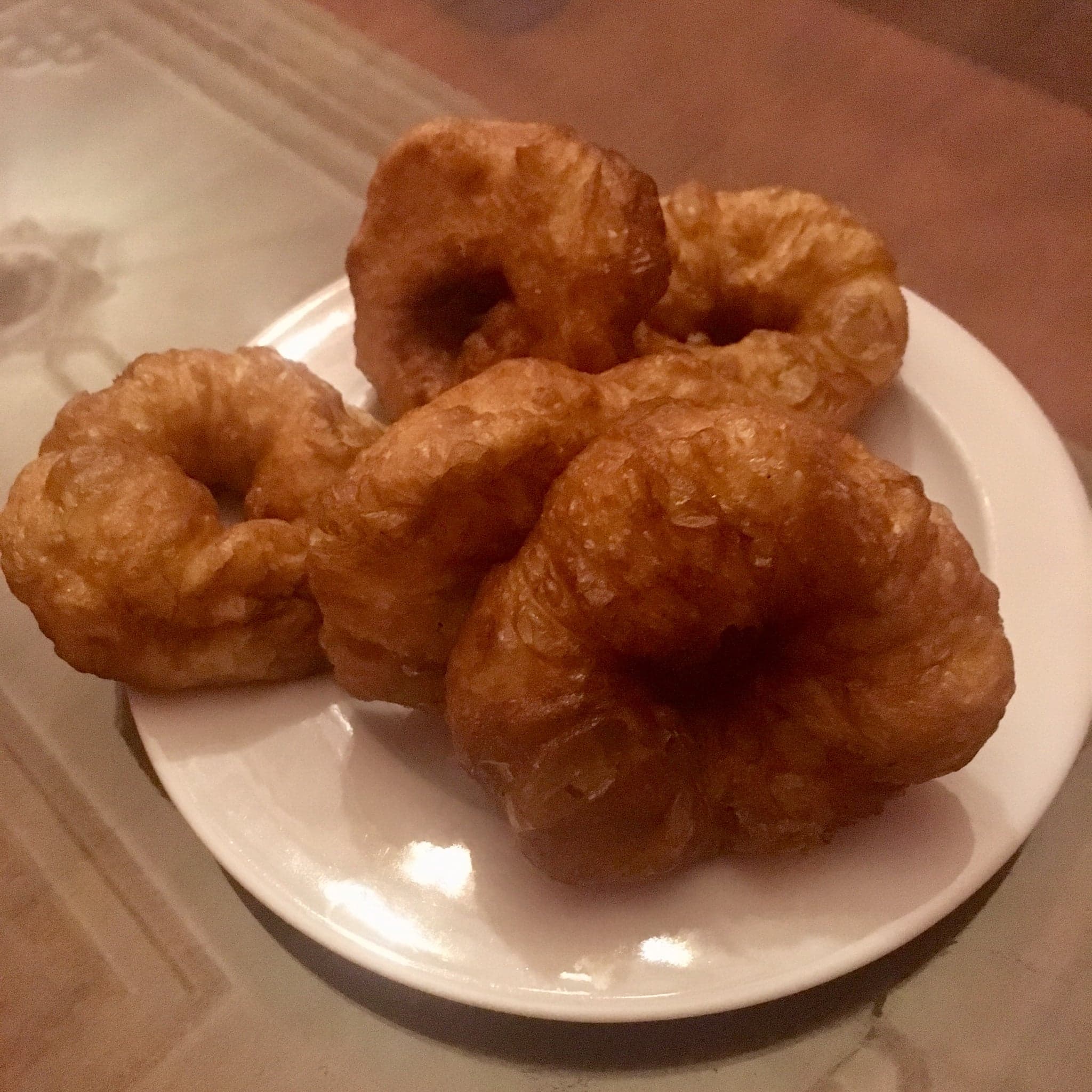 Golden fried sfinz doughnuts in a pile, some drizzled with honey and sprinkled with sesame