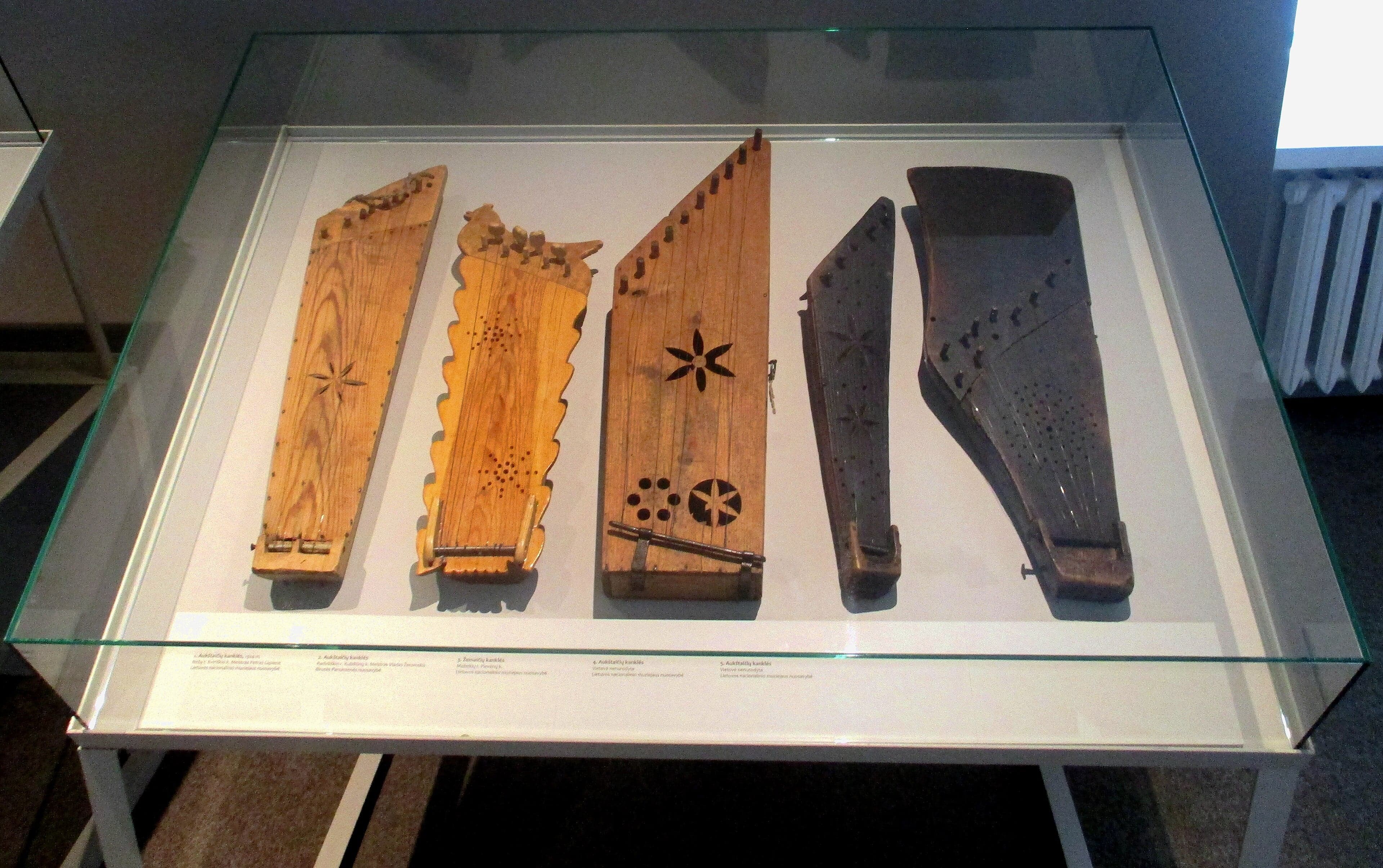 A traditional Lithuanian kanklės laid on a woven cloth, showing its carved wooden body and strings