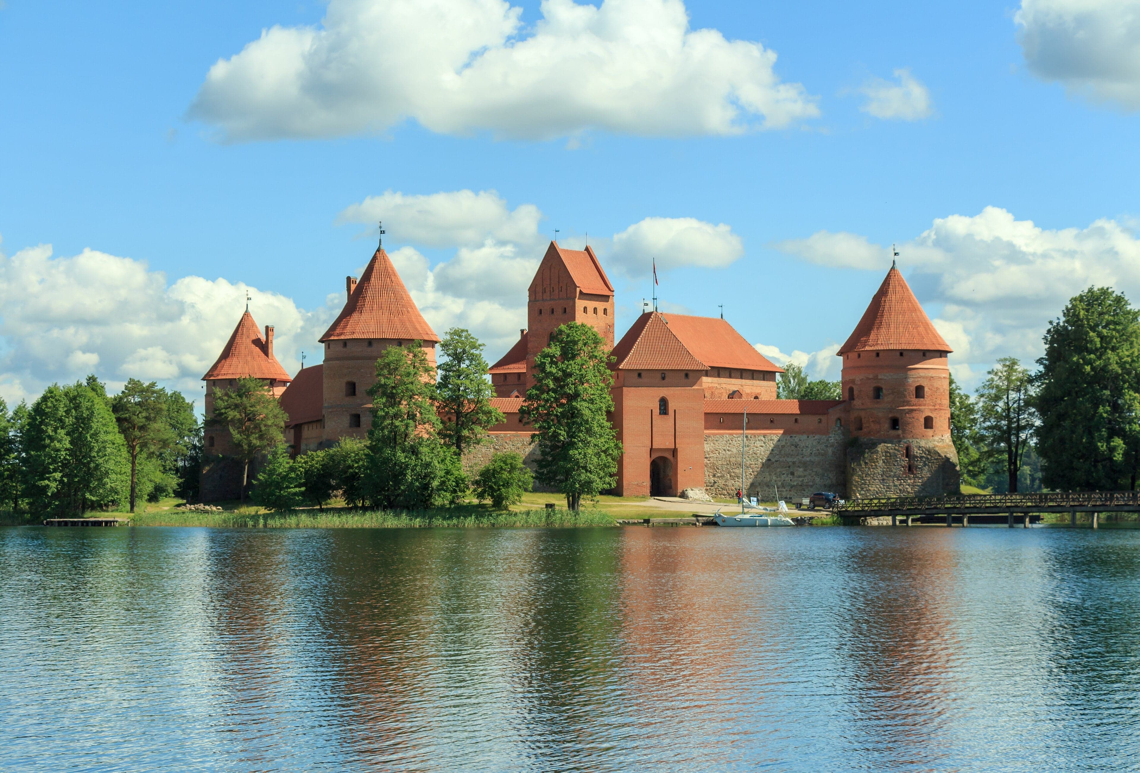 Trakai Island Castle rising from the blue waters of Lake Galvė, surrounded by pine trees