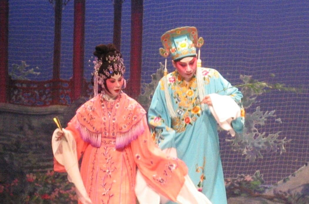 Cantonese opera performers in elaborate painted face makeup and colourful silk costumes on stage
