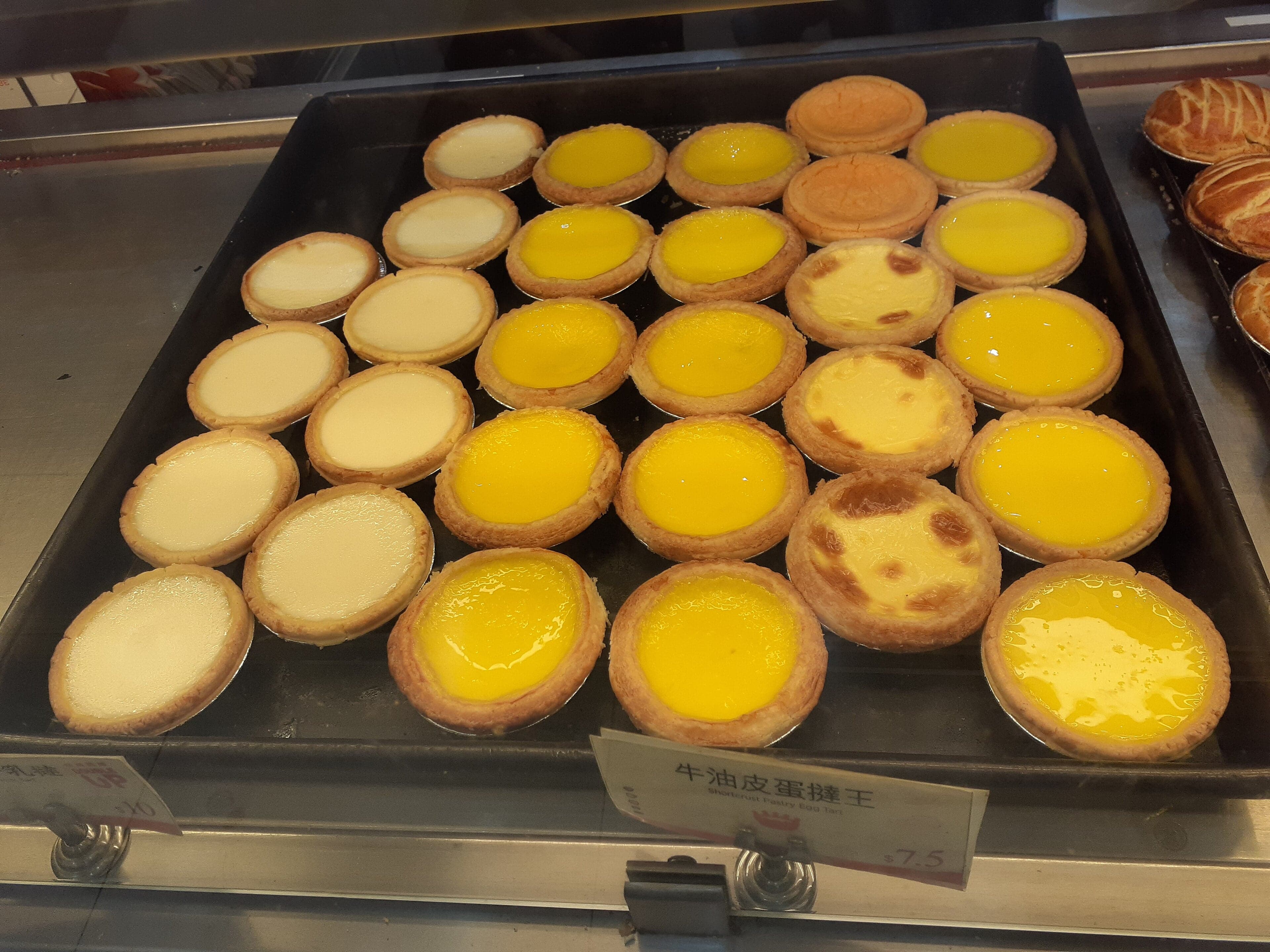 Three golden Macau egg tarts with slightly charred custard tops on a plate