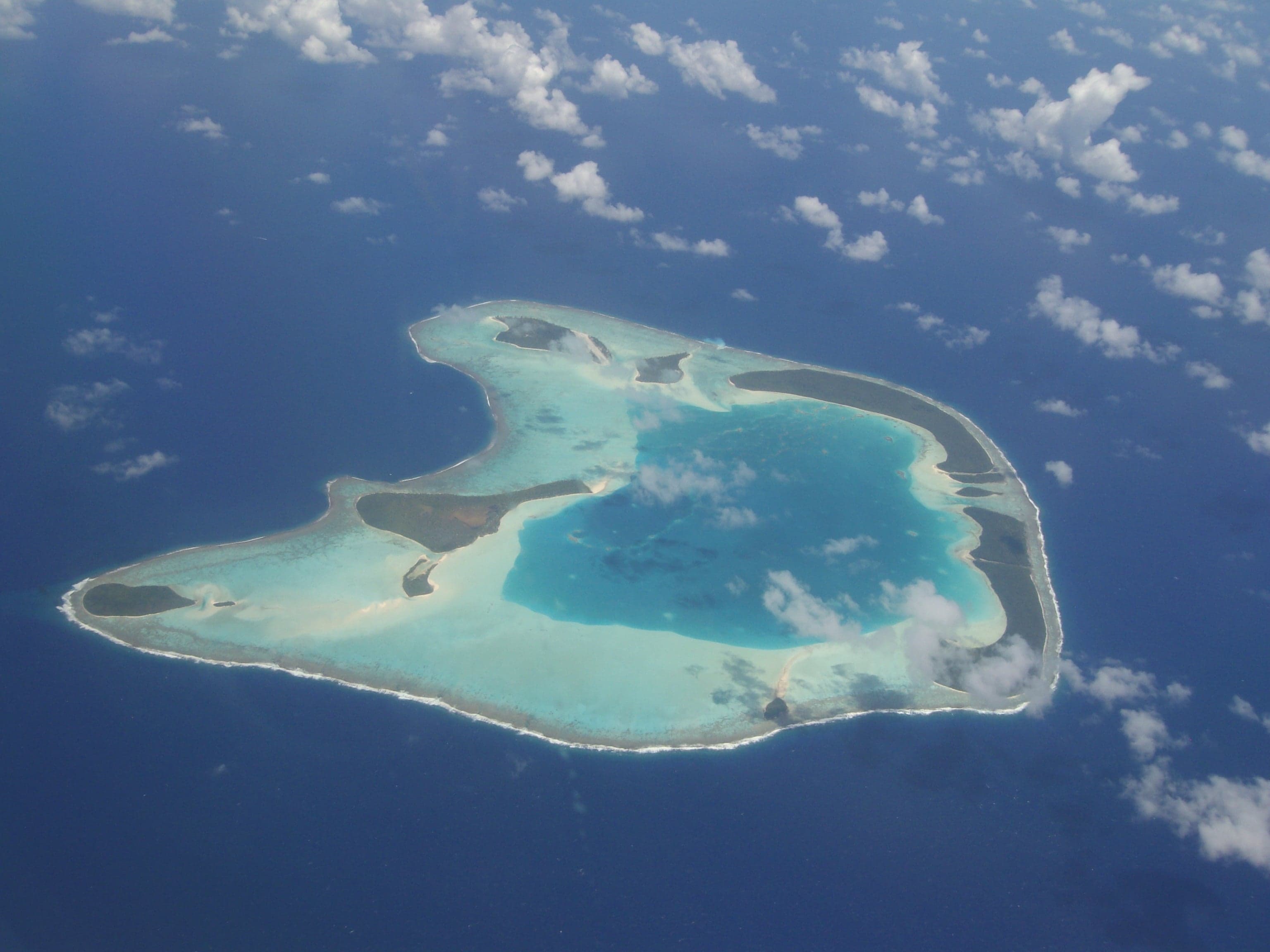 A ring-shaped atoll seen from the air, with tiny islands along its rim