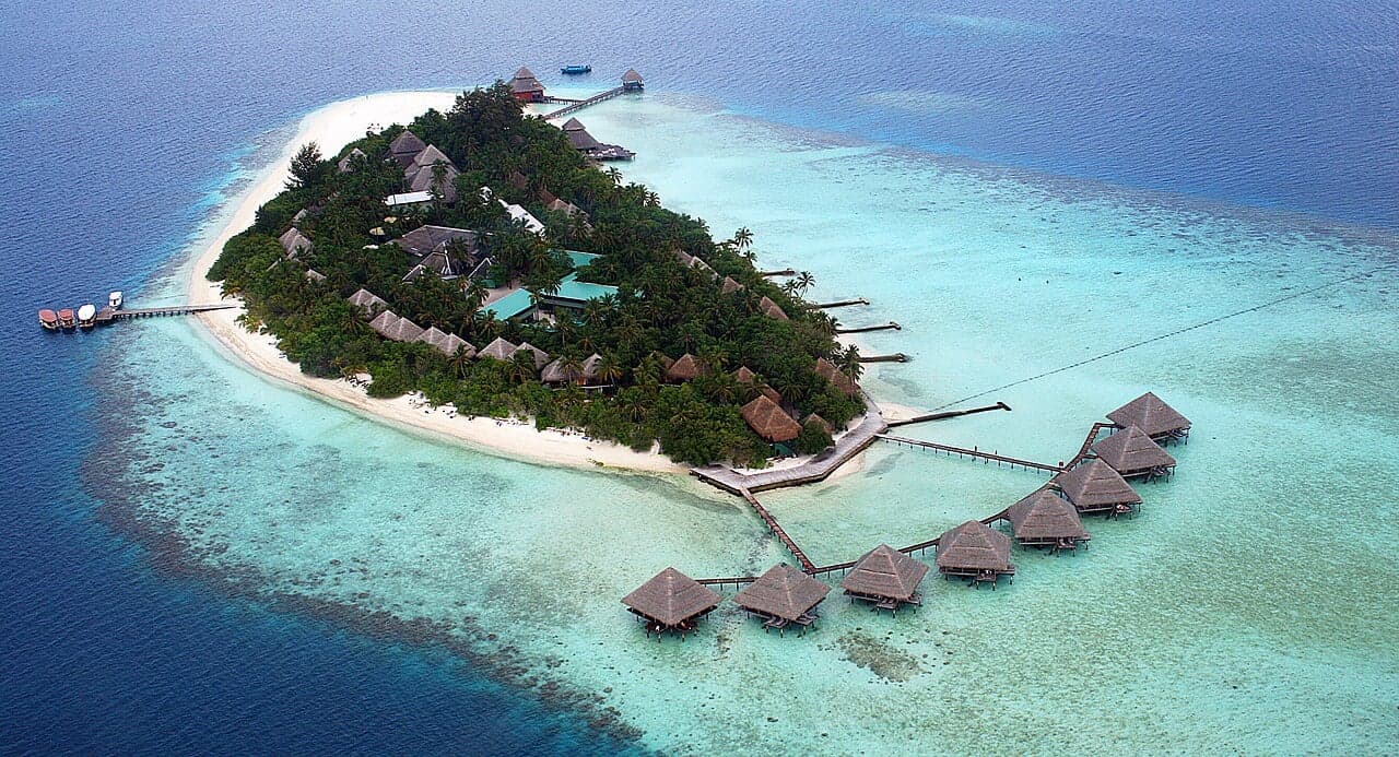 A tiny green island ringed by a white sandbank and turquoise lagoon