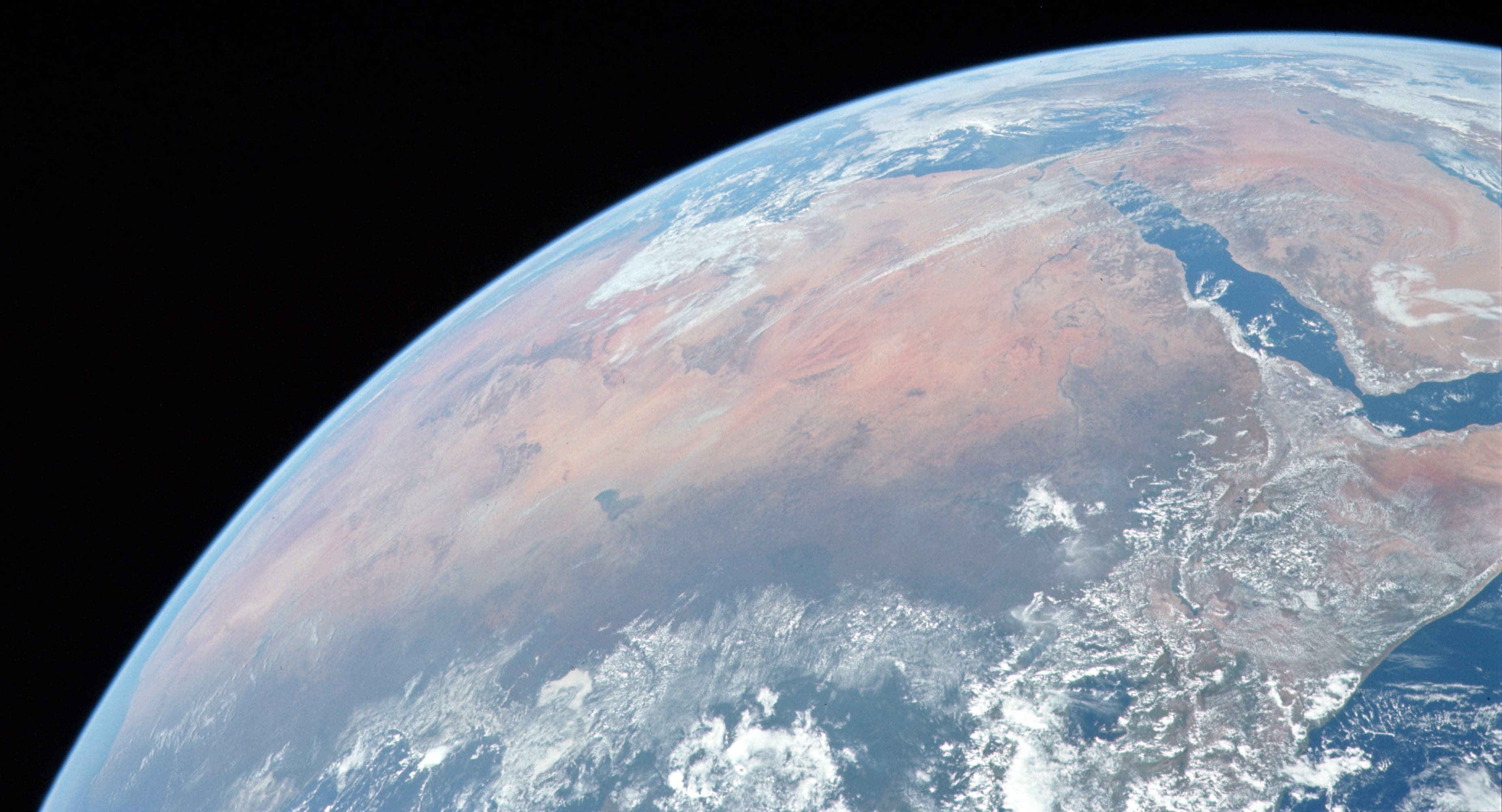 Enormous orange sand dunes rippling under a deep blue Saharan sky in Mali